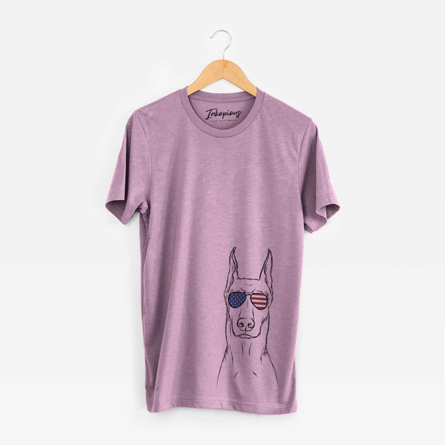 Hand-drawn sketch of Ace the Doberman Pinscher wearing American flag sunglasses on an Orchid Unisex crewneck