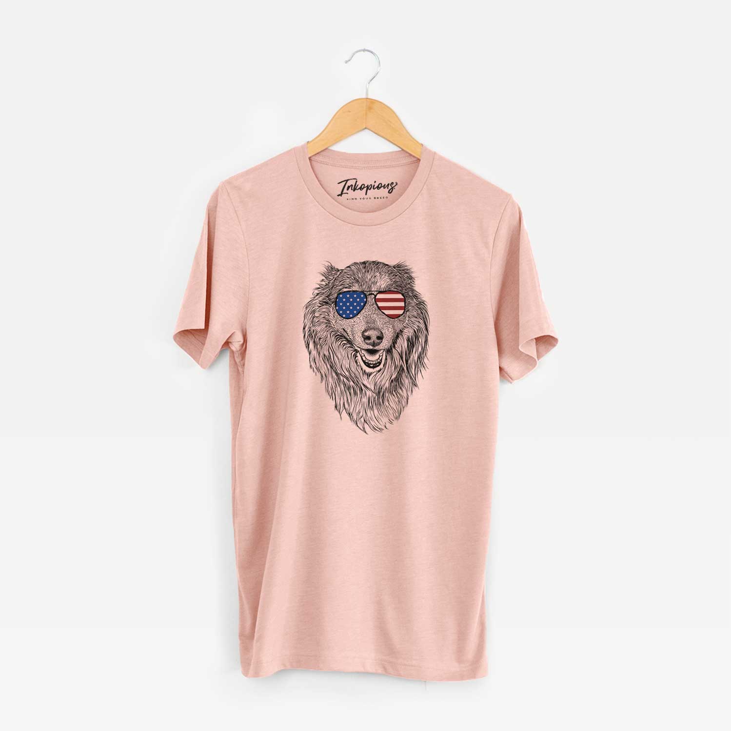 Hand-drawn sketch of Addie the Collie Mix wearing American flag sunglasses on a Peach Unisex crewneck