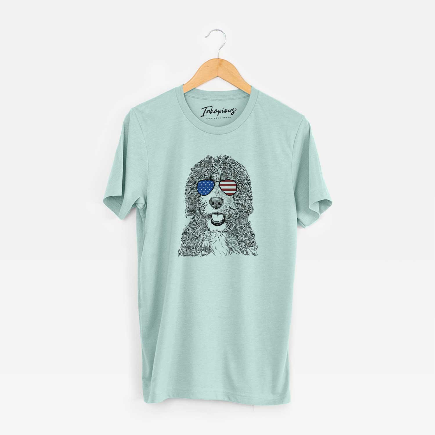 Hand-drawn sketch of Bash the Bernedoodle wearing American flag sunglasses on a Heather Sage Unisex crewneck