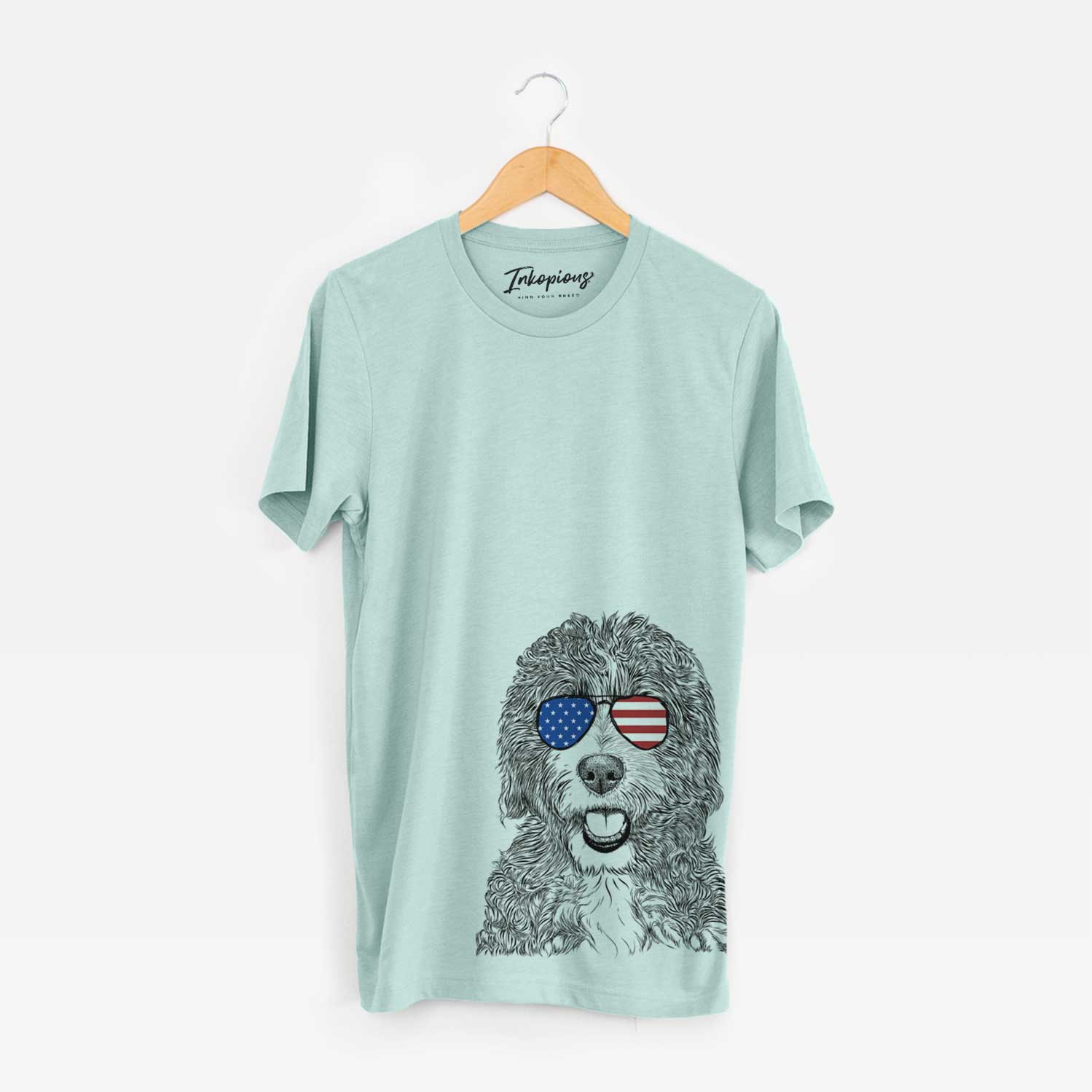 Hand-drawn sketch of Bash the Bernedoodle wearing American flag sunglasses on a Heather Sage Unisex crewneck