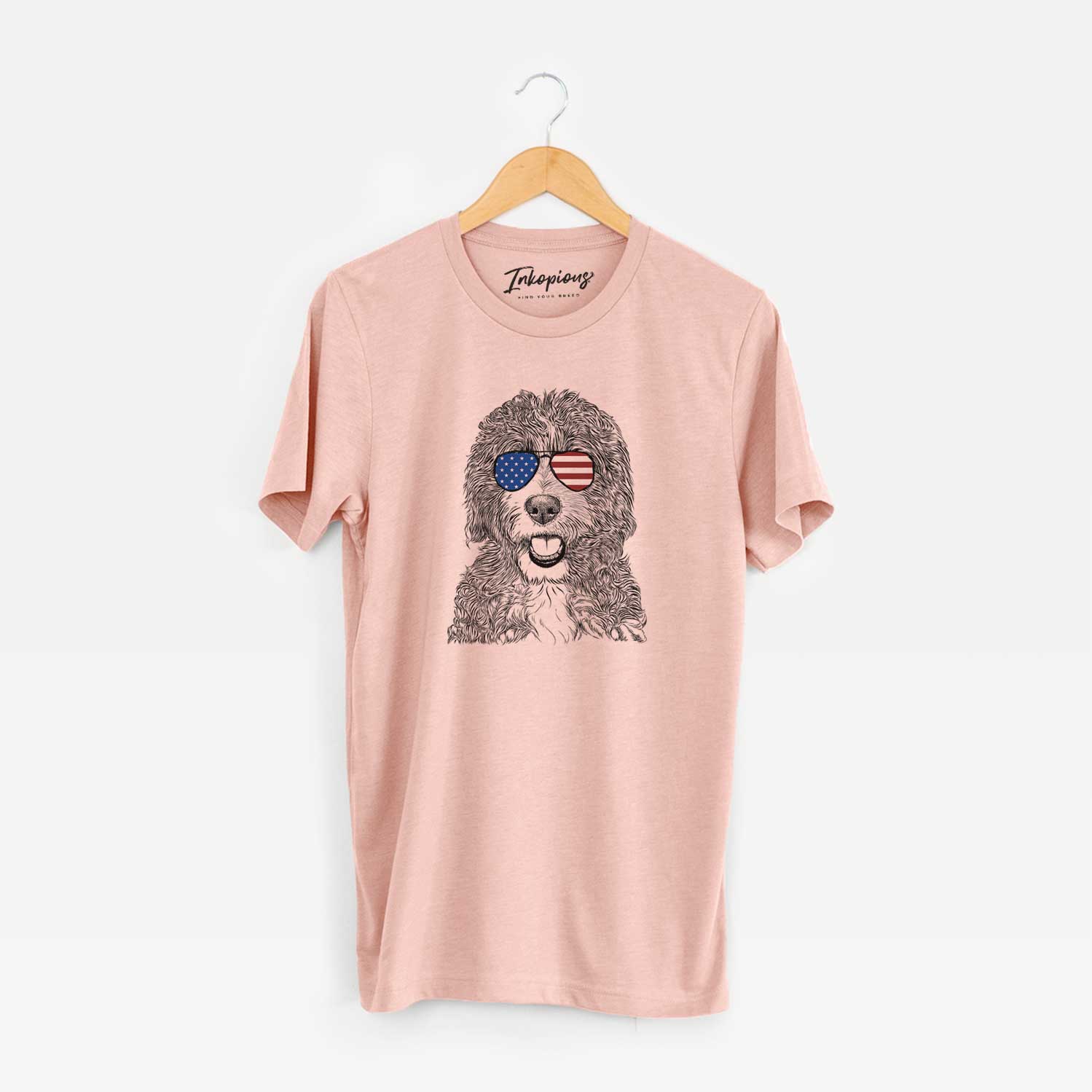 Hand-drawn sketch of Bash the Bernedoodle wearing American flag sunglasses on a Peach Unisex crewneck