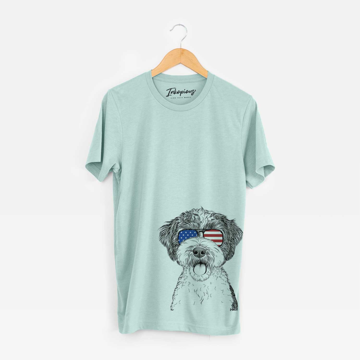 Hand-drawn sketch of Bella the Cockapoo wearing American flag sunglasses on a Heather Sage Unisex crewneck