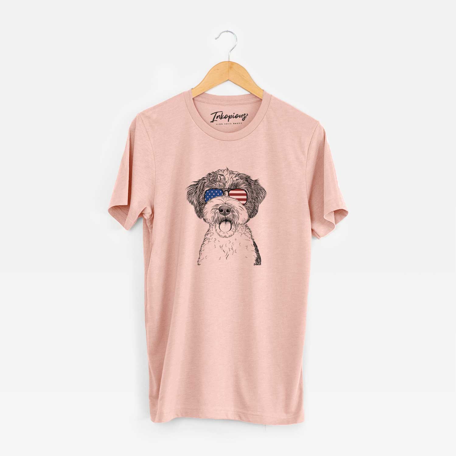 Hand-drawn sketch of Bella the Cockapoo wearing American flag sunglasses on a Peach Unisex crewneck