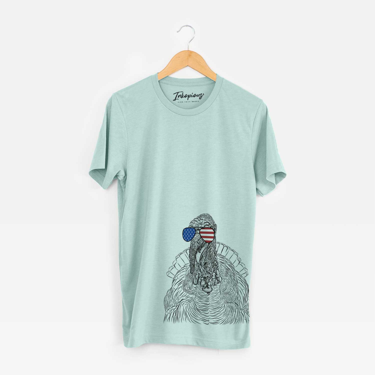Hand-drawn sketch of Brady the Turkey wearing American flag sunglasses on a Heather Sage Unisex crewneck