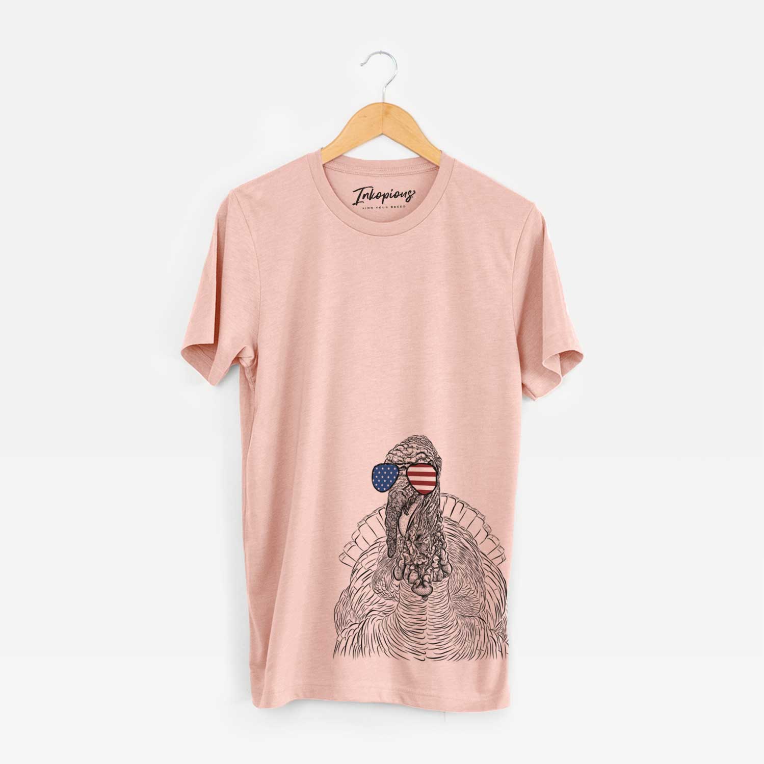 Hand-drawn sketch of Brady the Turkey wearing American flag sunglasses on a Peach Unisex crewneck