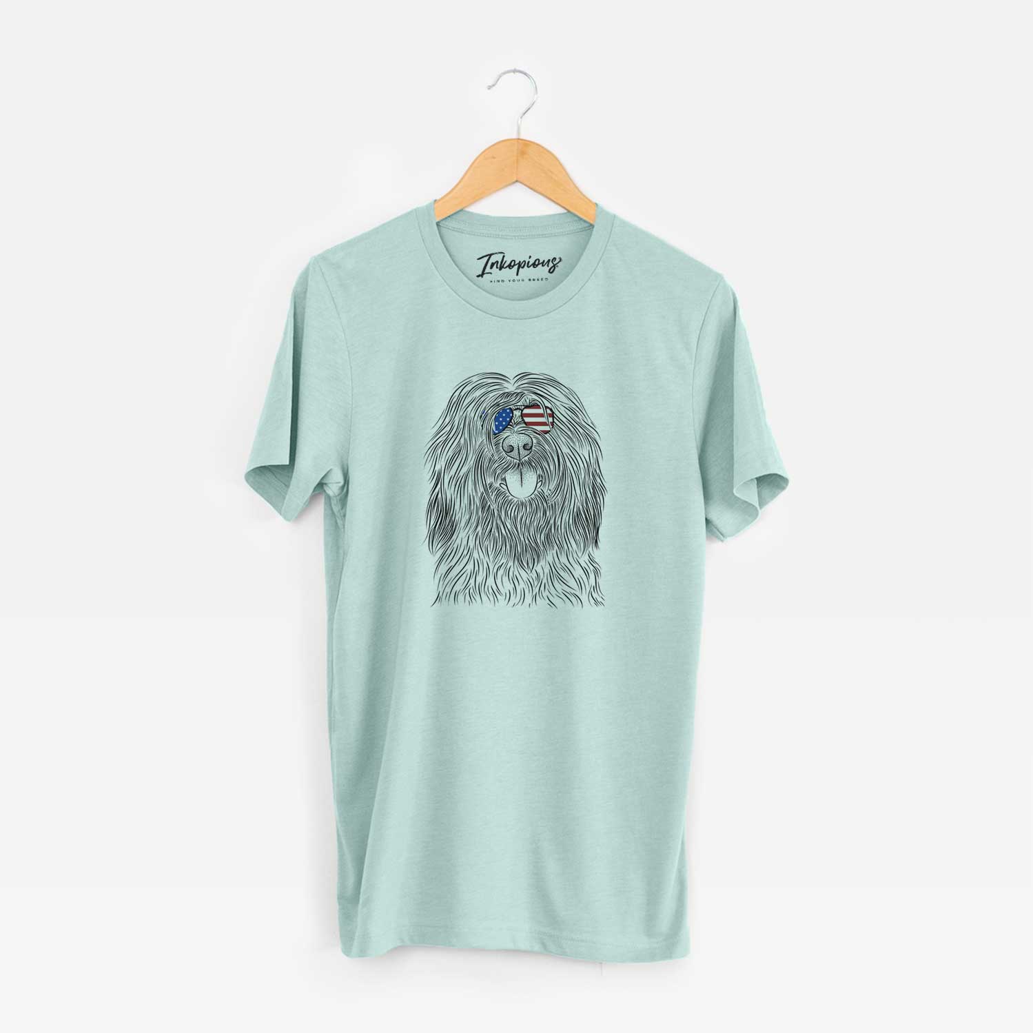Hand-drawn sketch of Bundy the Briard wearing American flag sunglasses on a Heather Sage Unisex crewneck