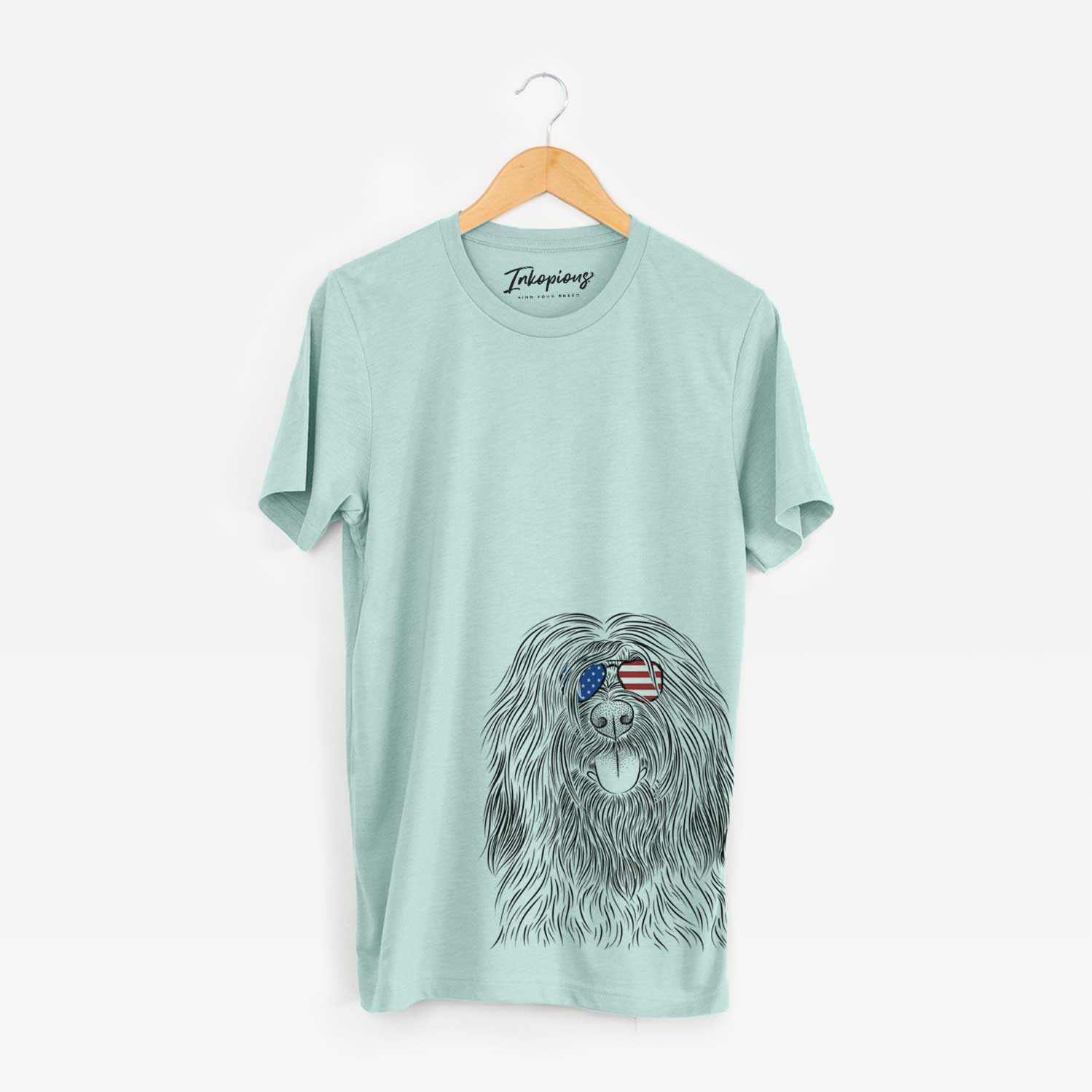Hand-drawn sketch of Bundy the Briard wearing American flag sunglasses on a Heather Sage Unisex crewneck