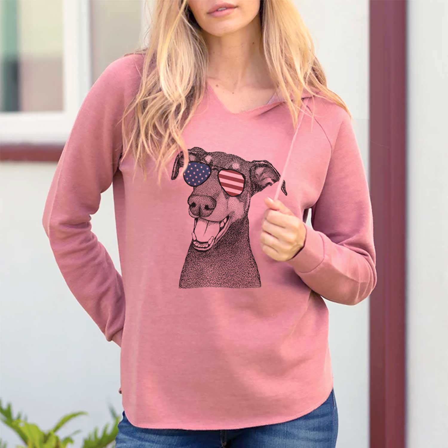 Hand-drawn sketch of Bunnie the Doberman Pinscher wearing American flag sunglasses on a Dusty Rose Cali Wave Hooded Sweatshirt, lifestyle photo
