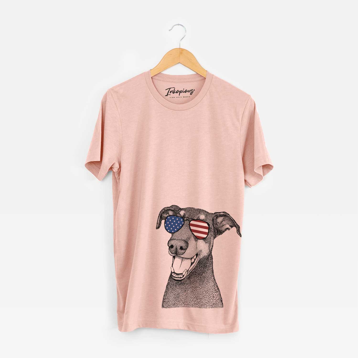 Hand-drawn sketch of Bunnie the Doberman Pinscher wearing American flag sunglasses on a Peach Unisex crewneck