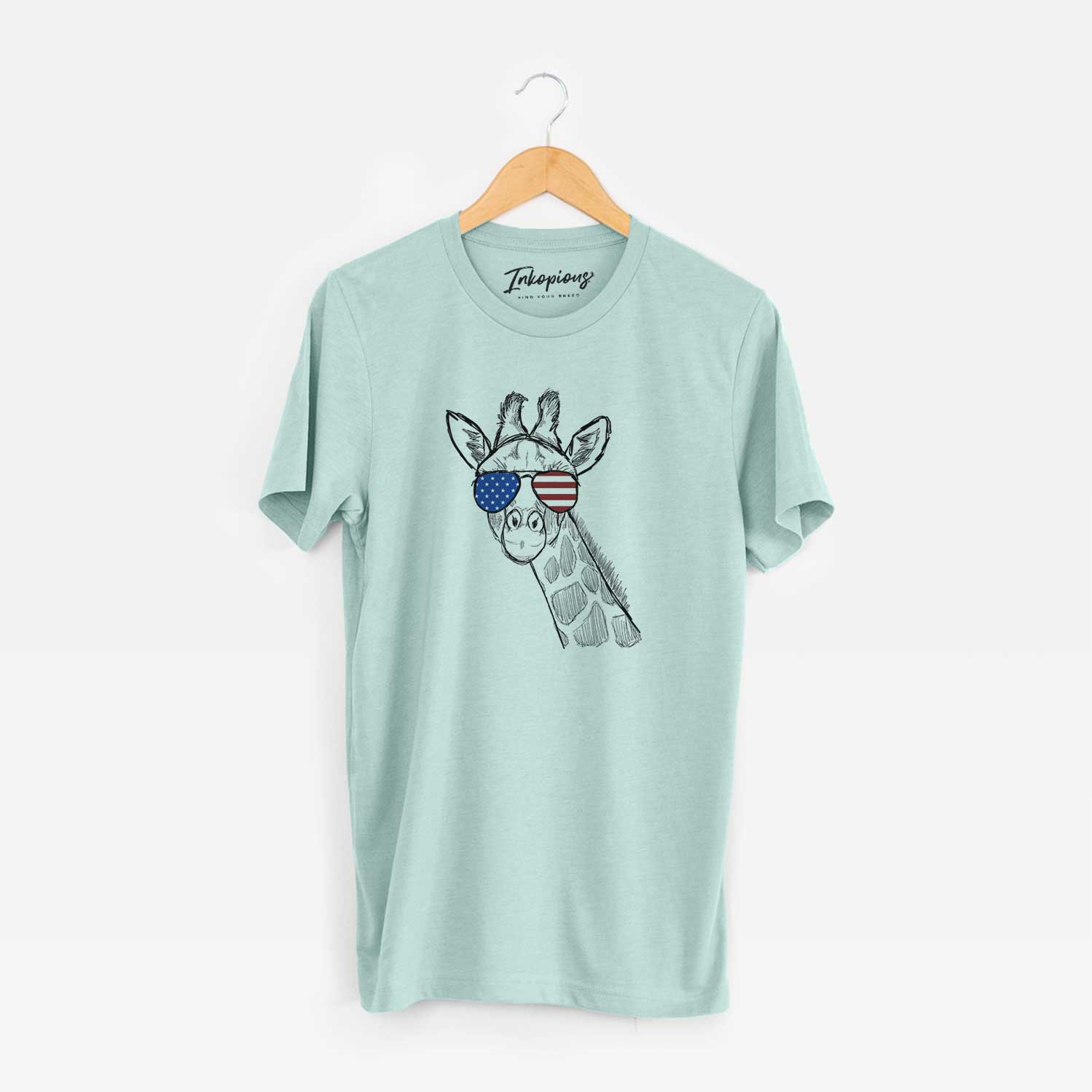Hand-drawn sketch of Cedrick the Giraffe wearing American flag sunglasses on a Heather Sage Unisex crewneck
