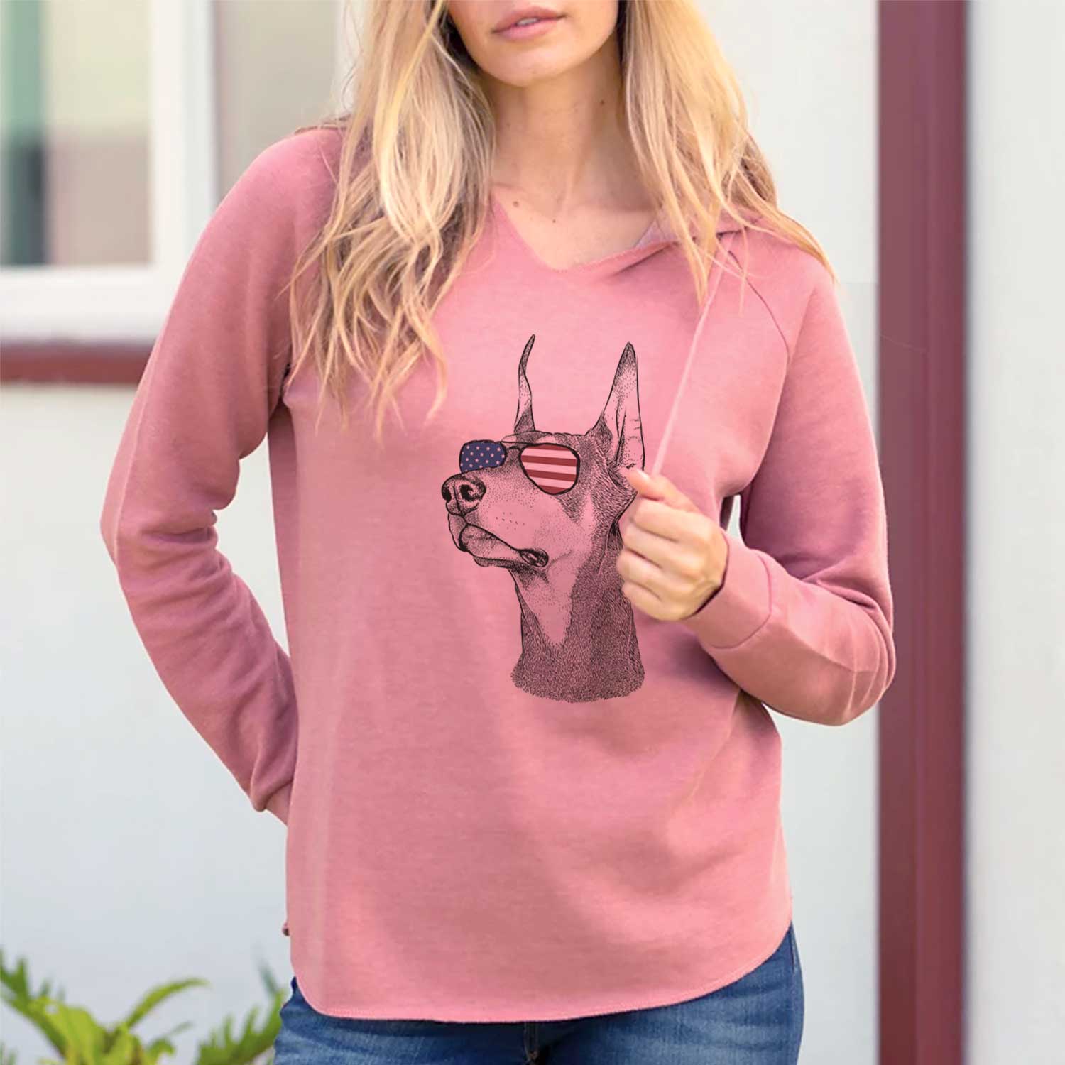 Hand-drawn sketch of Cenza the Doberman Pinscher wearing American flag sunglasses on a Dusty Rose Cali Wave Hooded Sweatshirt, lifestyle photo