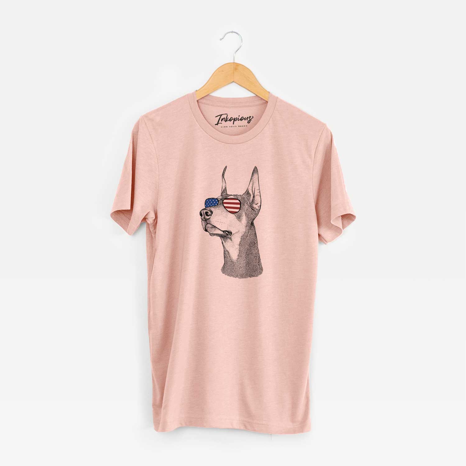Hand-drawn sketch of Cenza the Doberman Pinscher wearing American flag sunglasses on a Peach Unisex crewneck