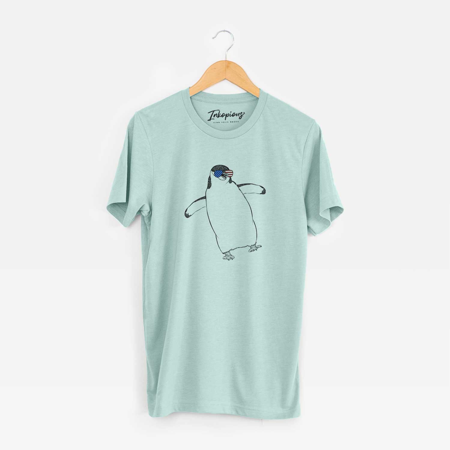 Hand-drawn sketch of Chive the Chinstrap Penguin wearing American flag sunglasses on a Heather Sage Unisex crewneck
