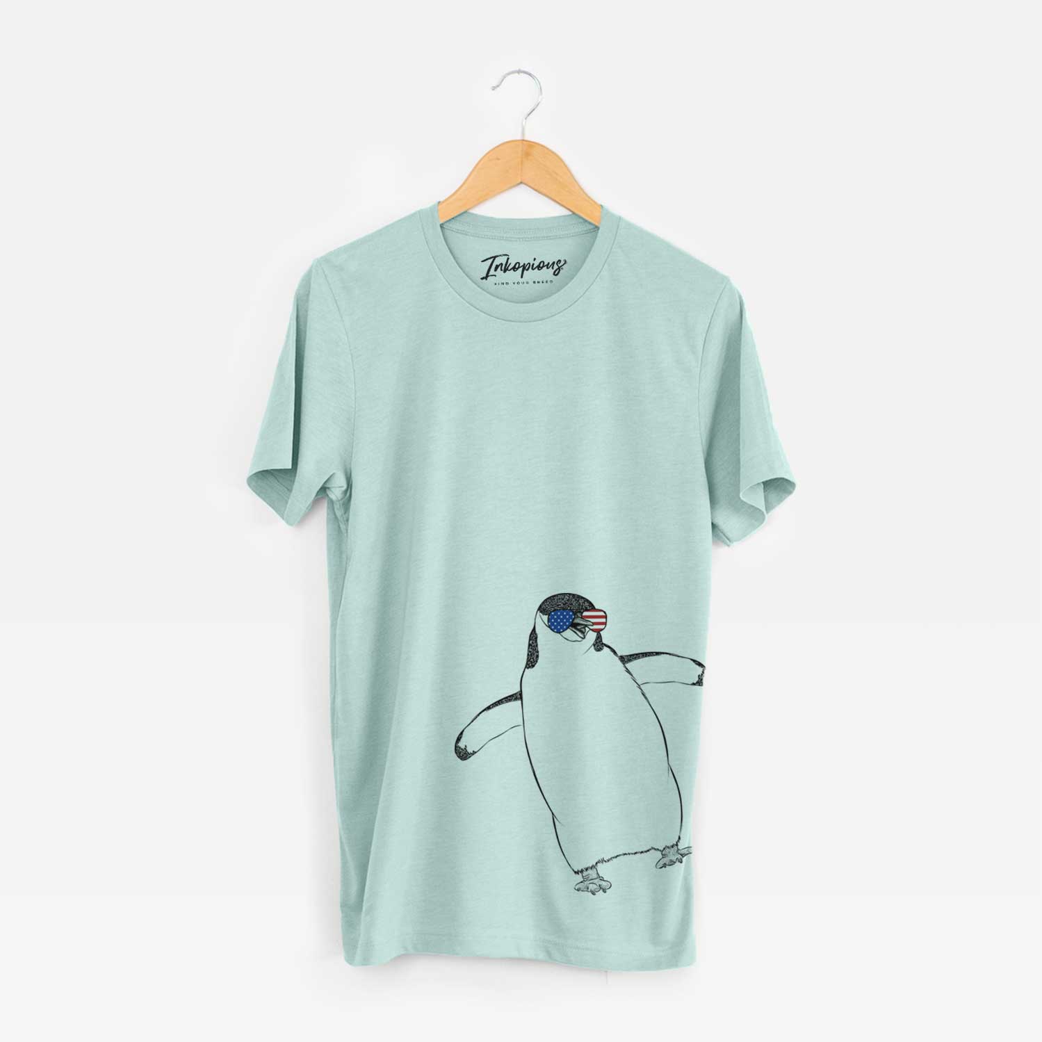 Hand-drawn sketch of Chive the Chinstrap Penguin wearing American flag sunglasses on a Heather Sage Unisex crewneck