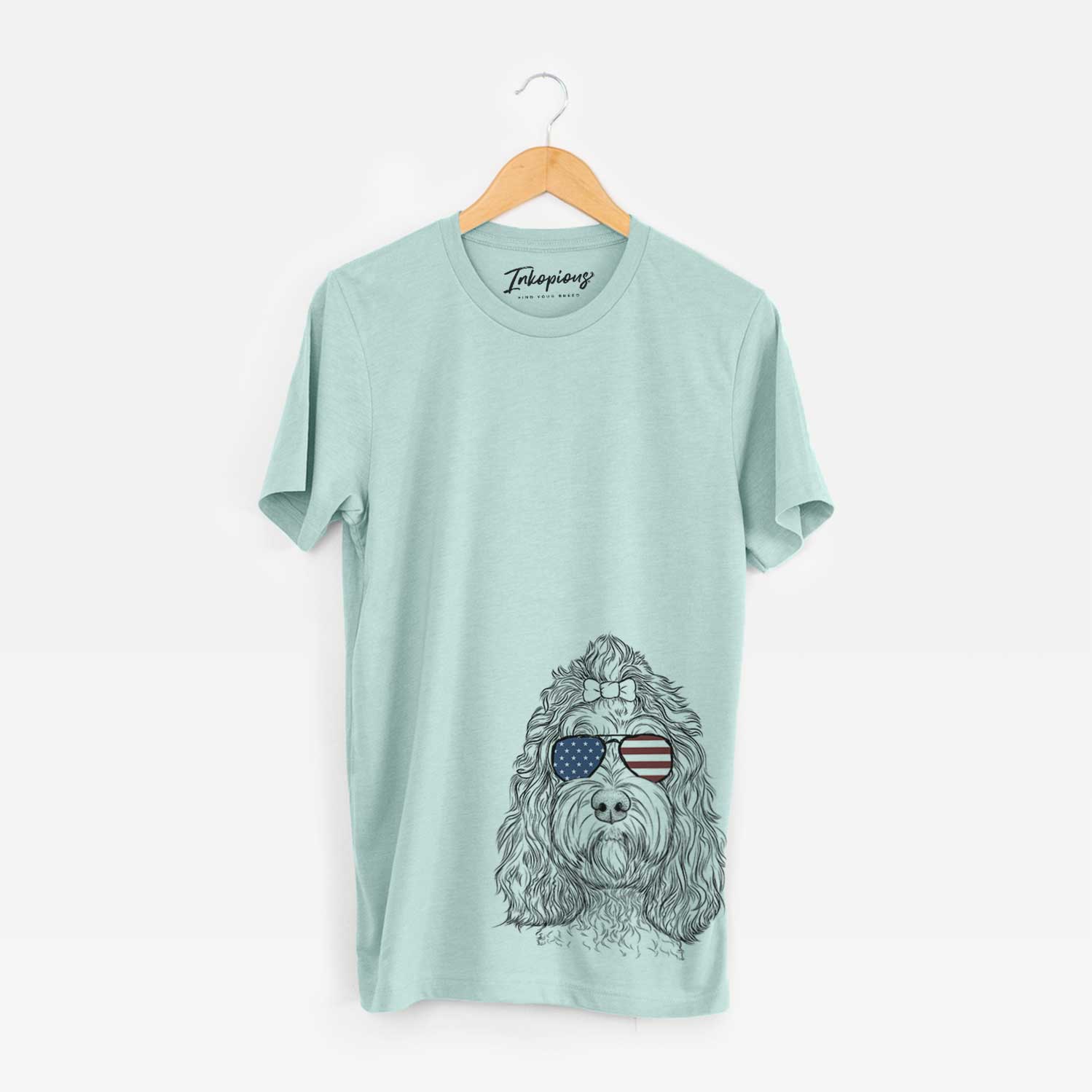 Hand-drawn sketch of Chloe the Cockapoo wearing American flag sunglasses on a Heather Sage Unisex crewneck