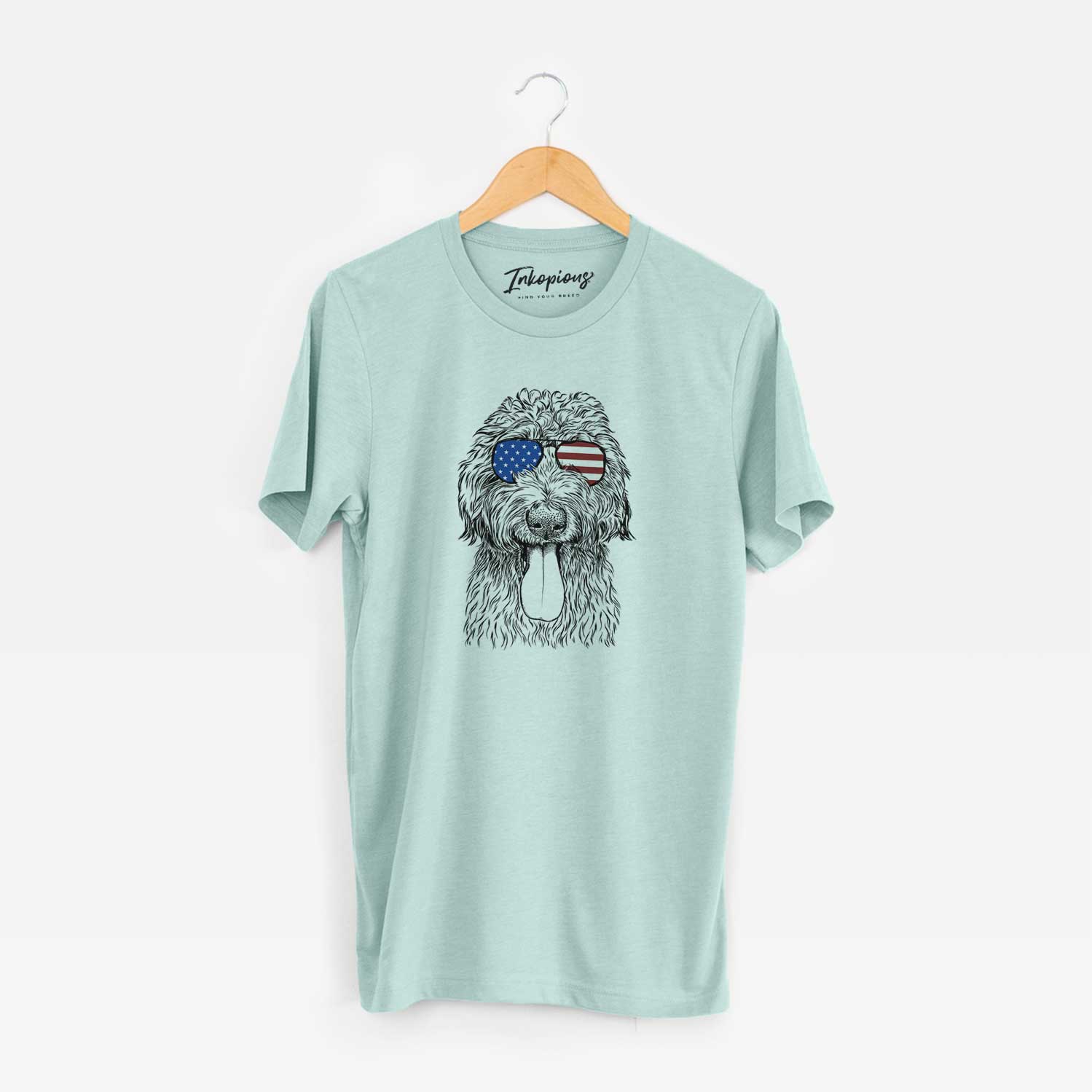 Hand-drawn sketch of CiCi Paulk the Aussiedoodle wearing American flag sunglasses on a Heather Sage Unisex crewneck