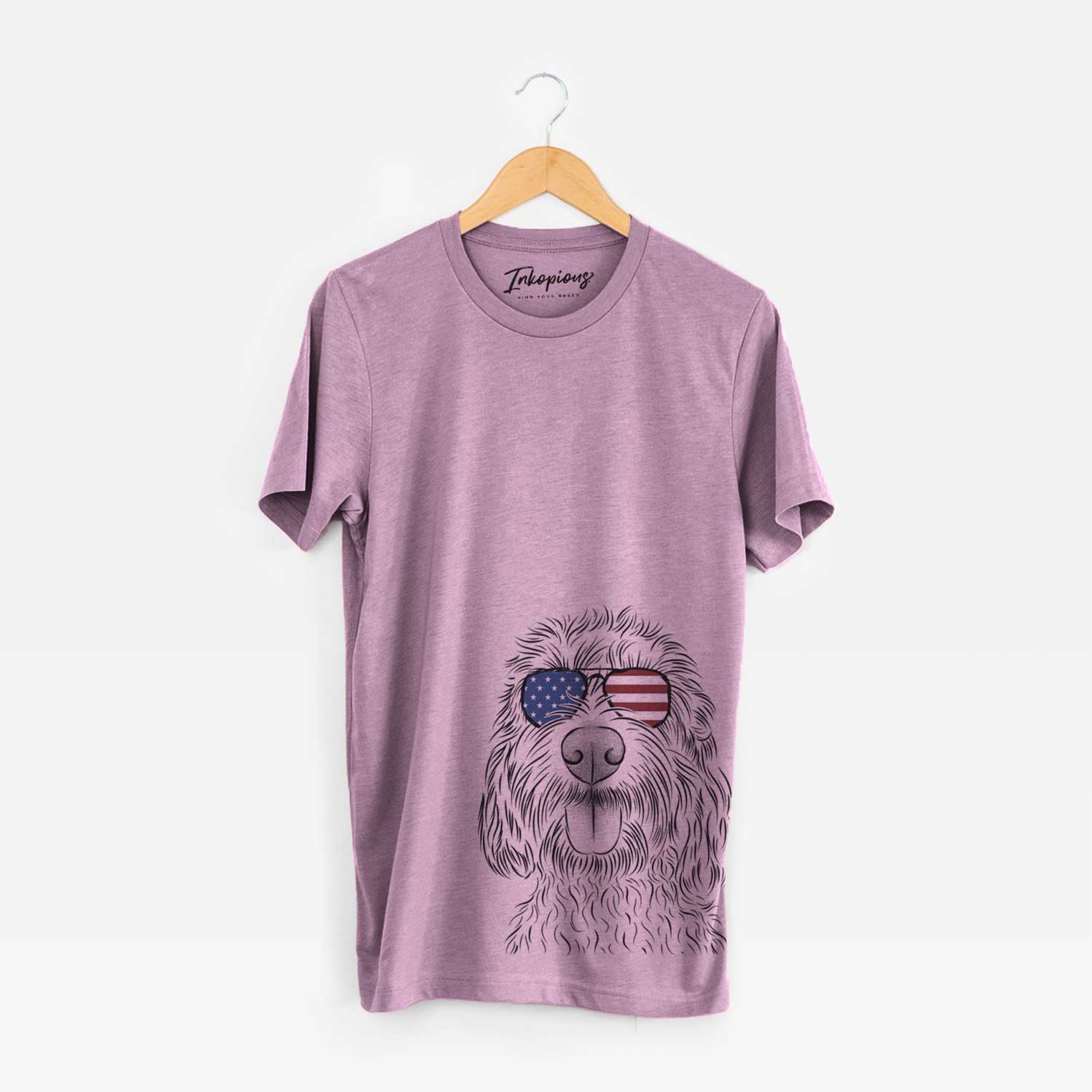 Hand-drawn sketch of Clover the Cockapoo wearing American flag sunglasses on an Orchid Unisex crewneck