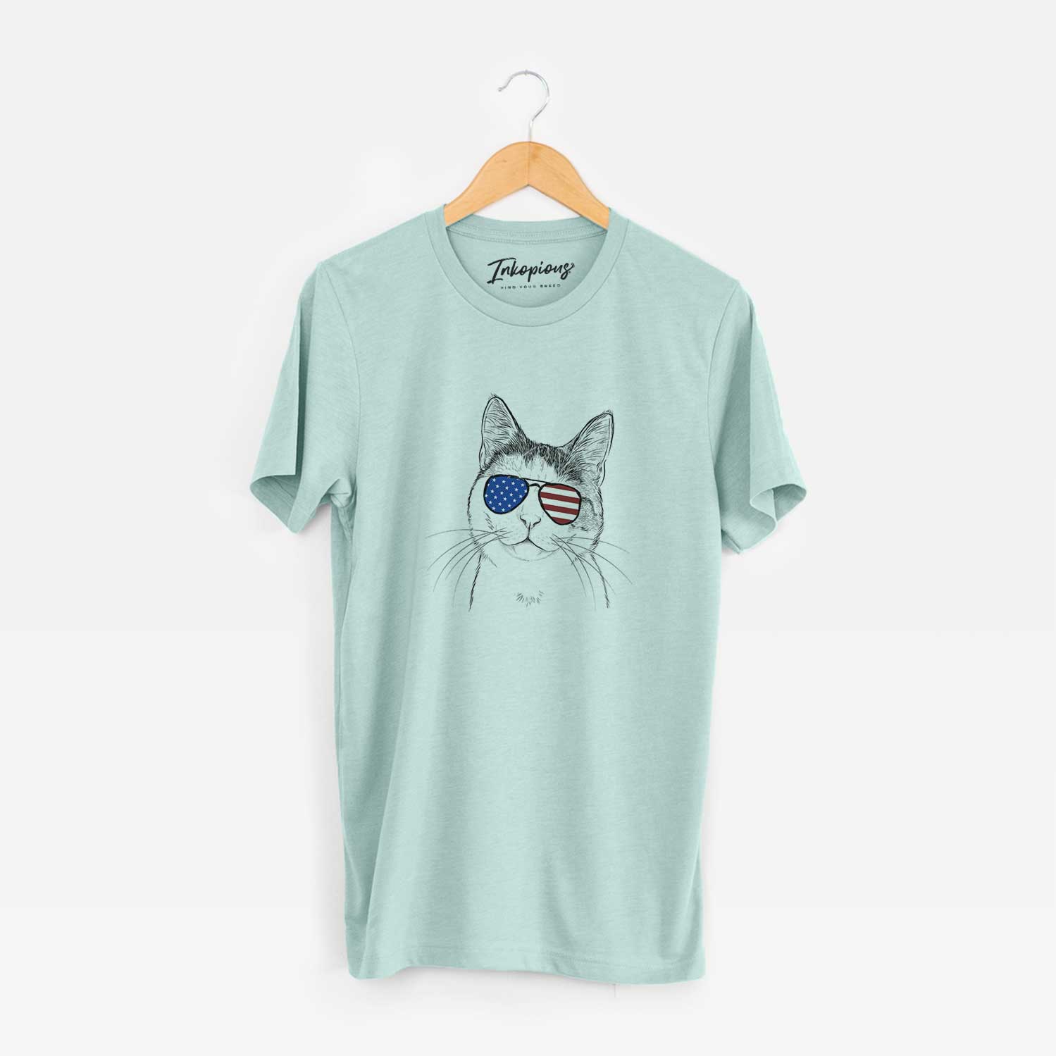 Hand-drawn sketch of Denver the Calico Cat wearing American flag sunglasses on a Heather Sage Unisex crewneck