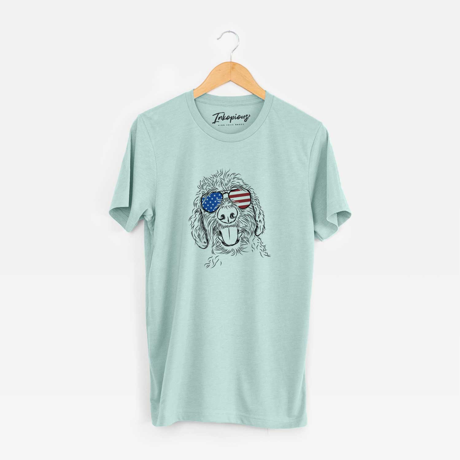 Hand-drawn sketch of Dixie the Doodle wearing American flag sunglasses on a Heather Sage Unisex crewneck