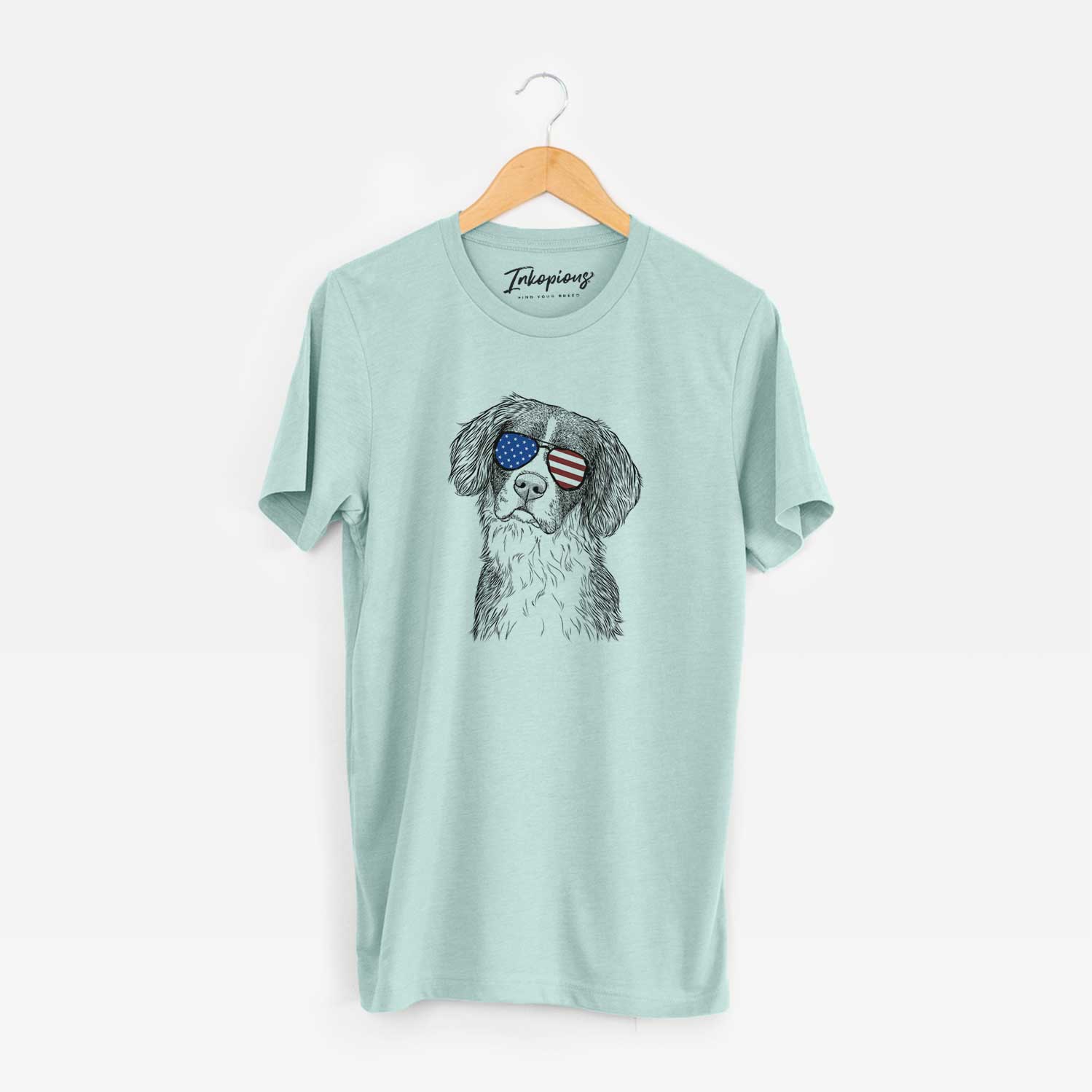 Hand-drawn sketch of Dulce the Drentsche Patrijshond wearing American flag sunglasses on a Heather Sage Unisex crewneck