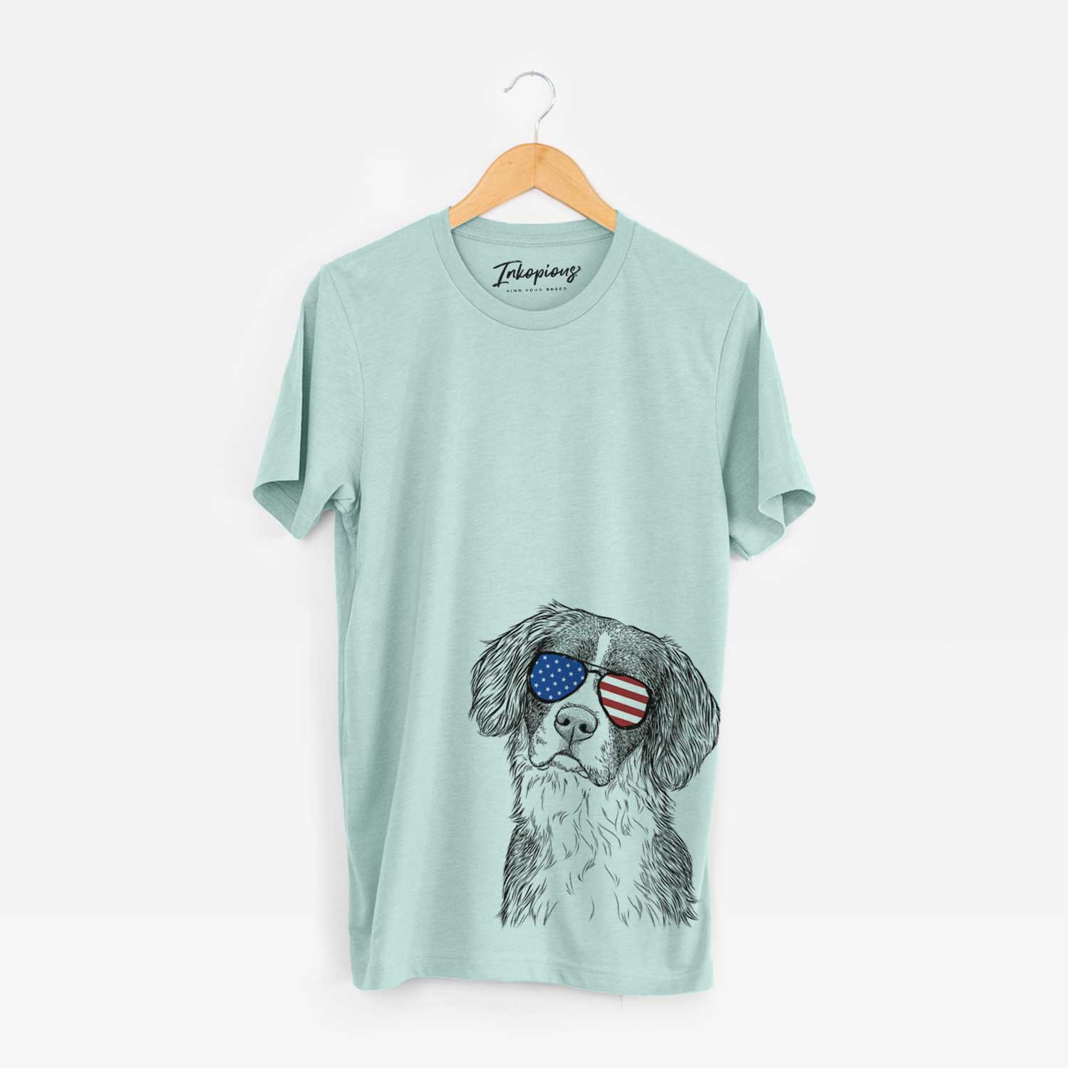 Hand-drawn sketch of Dulce the Drentsche Patrijshond wearing American flag sunglasses on a Heather Sage Unisex crewneck
