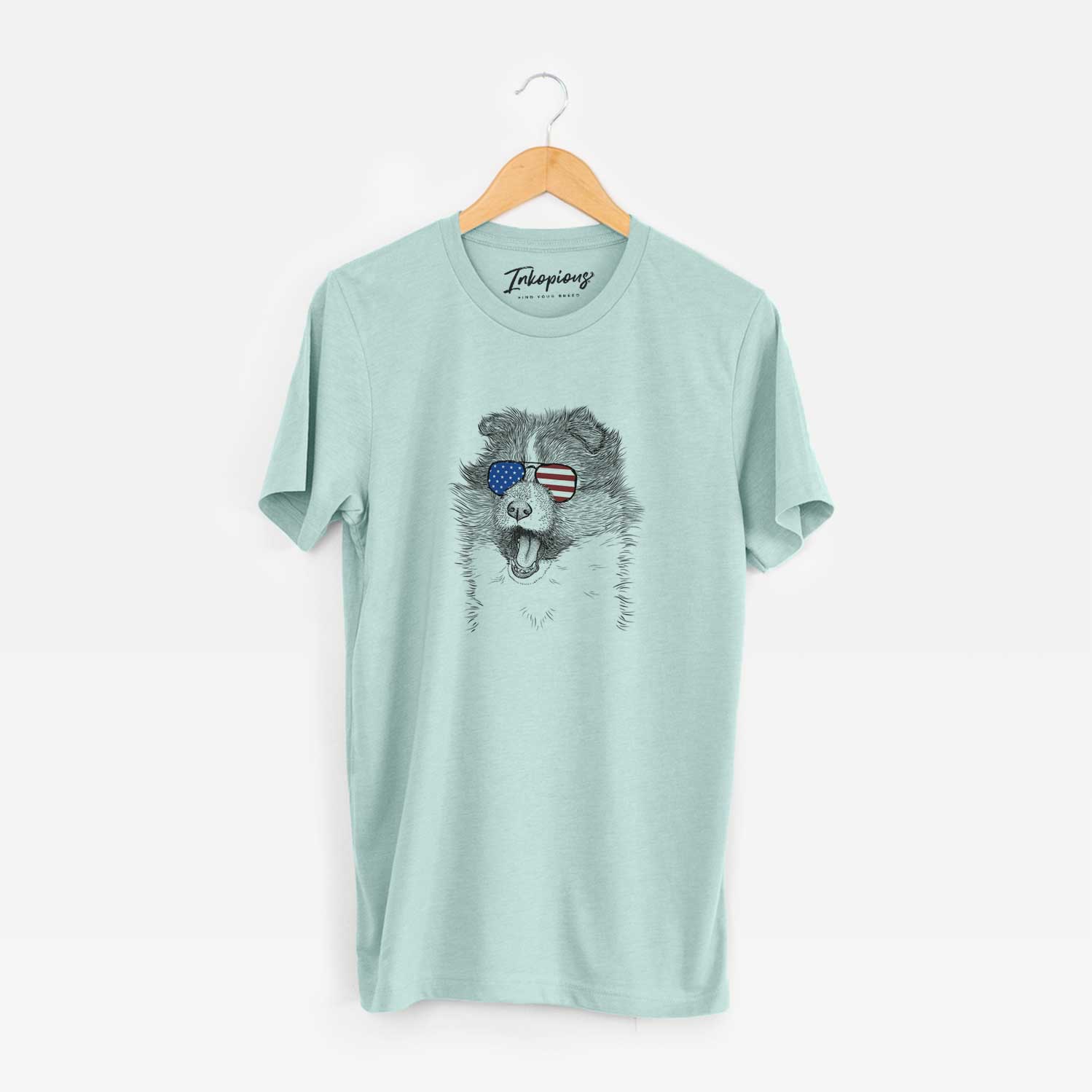 Hand-drawn sketch of Dylan the Shetland Sheepdog wearing American flag sunglasses on a Heather Sage Unisex crewneck