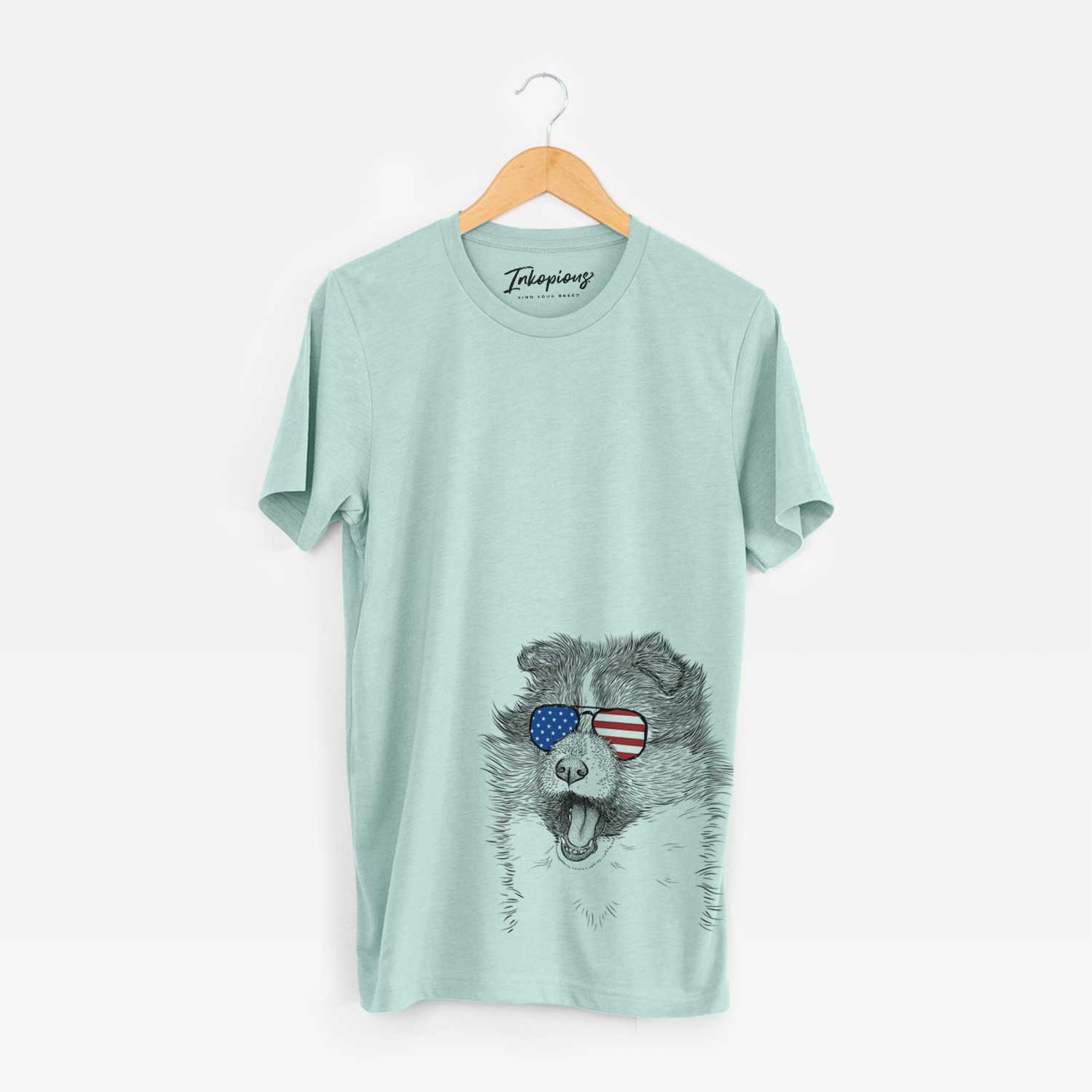 Hand-drawn sketch of Dylan the Shetland Sheepdog wearing American flag sunglasses on a Heather Sage Unisex crewneck