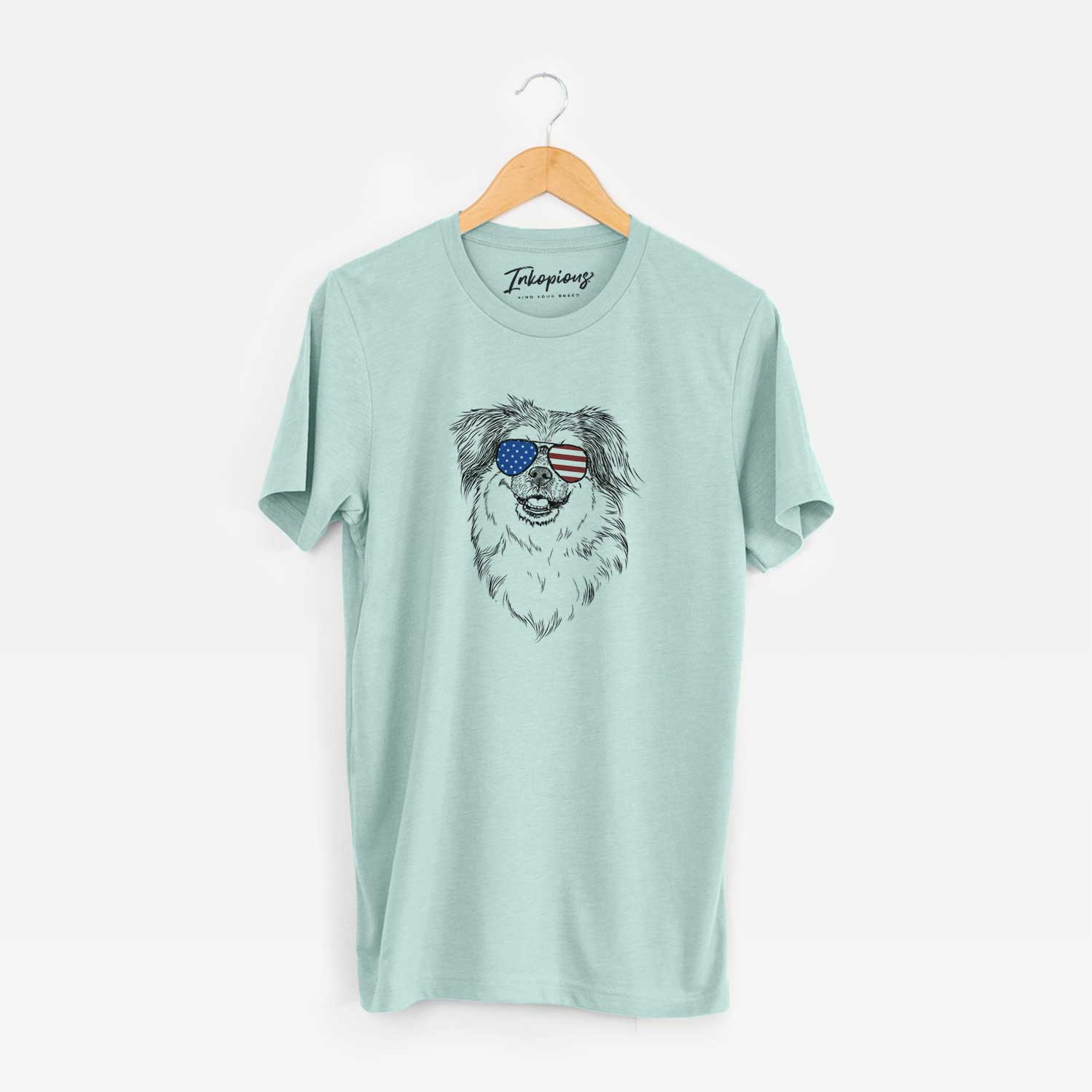 Hand-drawn sketch of Ed the Tibetan Spaniel wearing American flag sunglasses on a Heather Sage Unisex crewneck