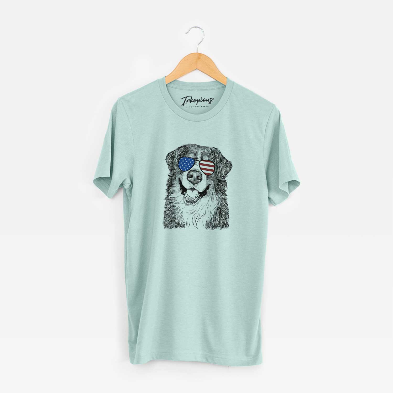 Hand-drawn sketch of Eiger the Bernese Mountain Dog wearing American flag sunglasses on a Heather Sage Unisex crewneck