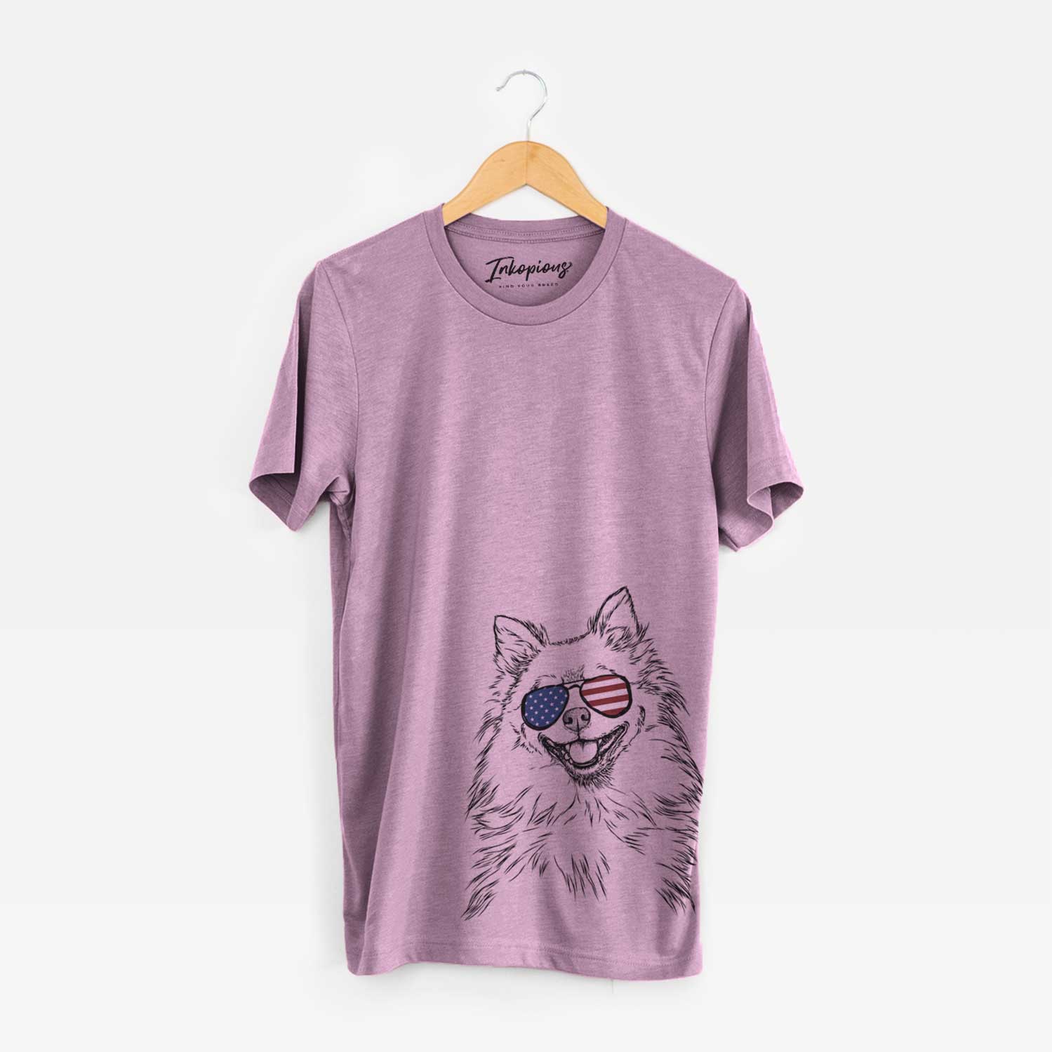 Hand-drawn sketch of Fibi the Spitz wearing American flag sunglasses on an Orchid Unisex crewneck