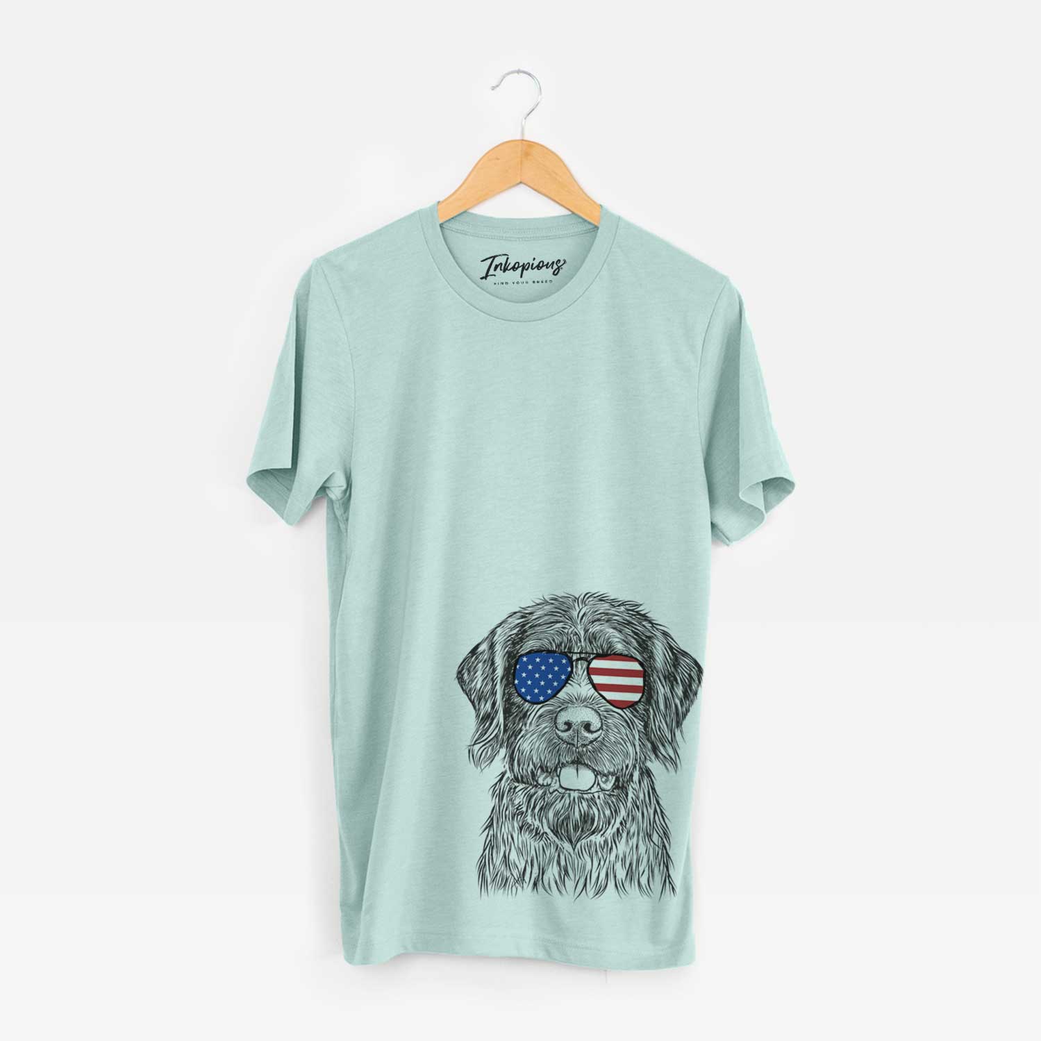 Hand-drawn sketch of Fletcher the Wirehaired Pointing Griffon wearing American flag sunglasses on a Heather Sage Unisex crewneck