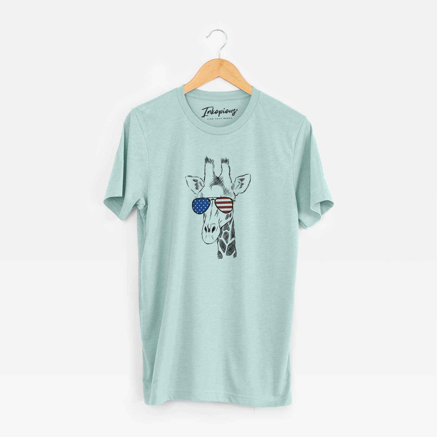 Hand-drawn sketch of Geoffrey the Giraffe wearing American flag sunglasses on a Heather Sage Unisex crewneck