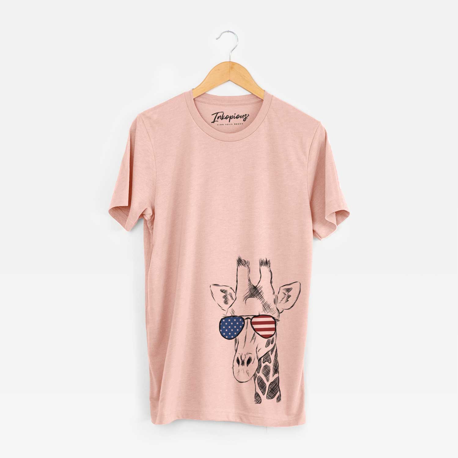Hand-drawn sketch of Geoffrey the Giraffe wearing American flag sunglasses on a Peach Unisex crewneck