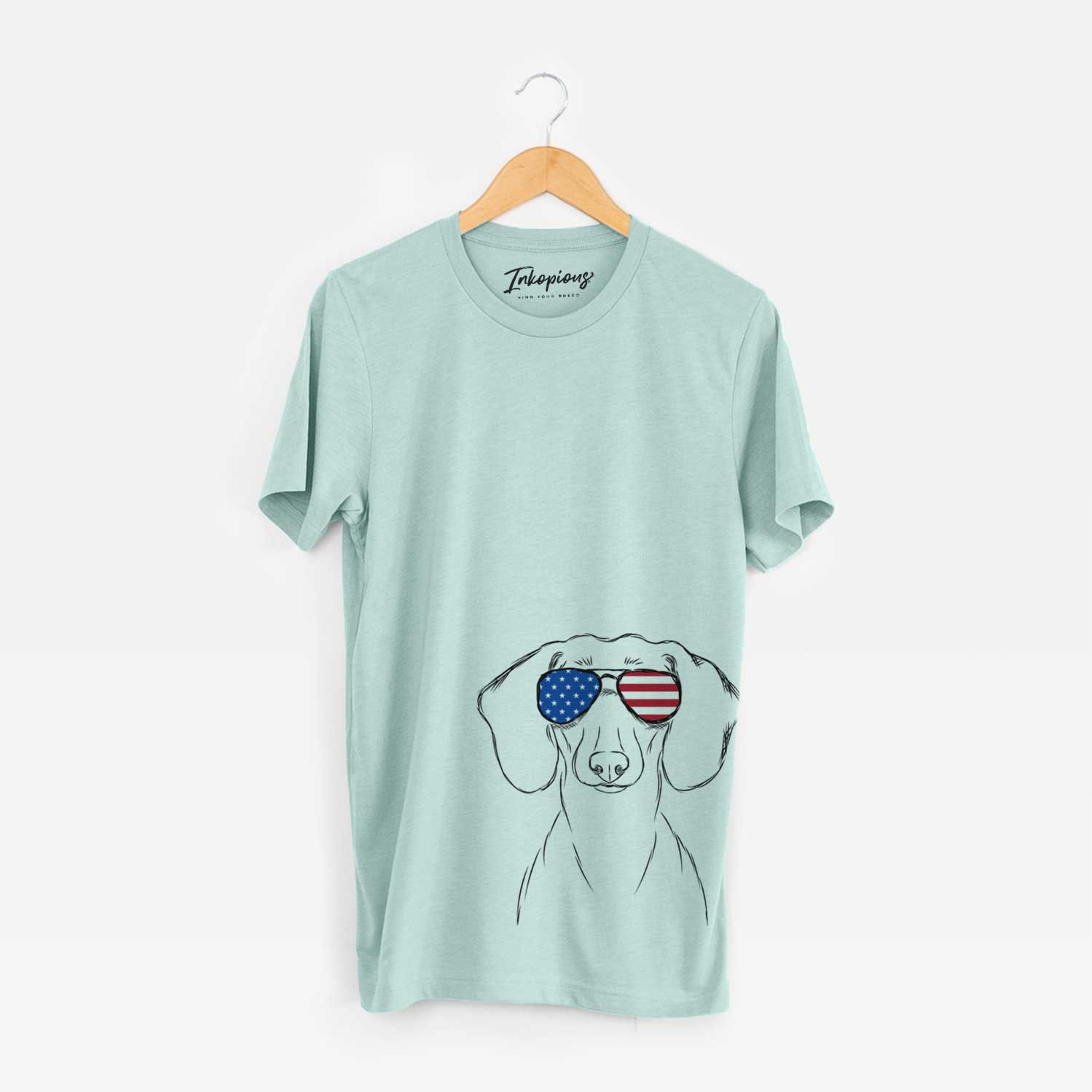 Hand-drawn sketch of Hans the Dachshund wearing American flag sunglasses on a Heather Sage Unisex crewneck