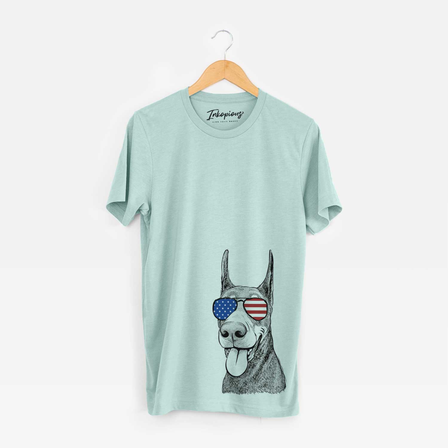 Hand-drawn sketch of Happy Sunny the Doberman Pinscher wearing American flag sunglasses on a Heather Sage Unisex crewneck