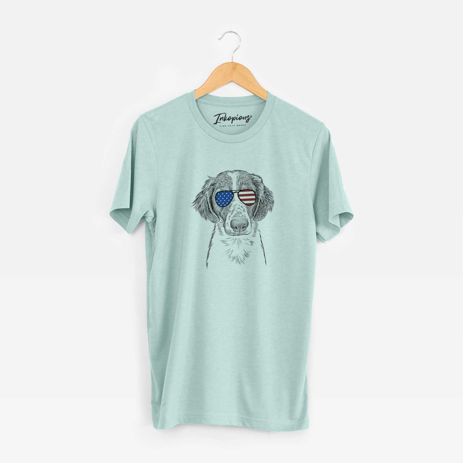 Hand-drawn sketch of Holly the Brittany Spaniel wearing American flag sunglasses on a Heather Sage Unisex crewneck