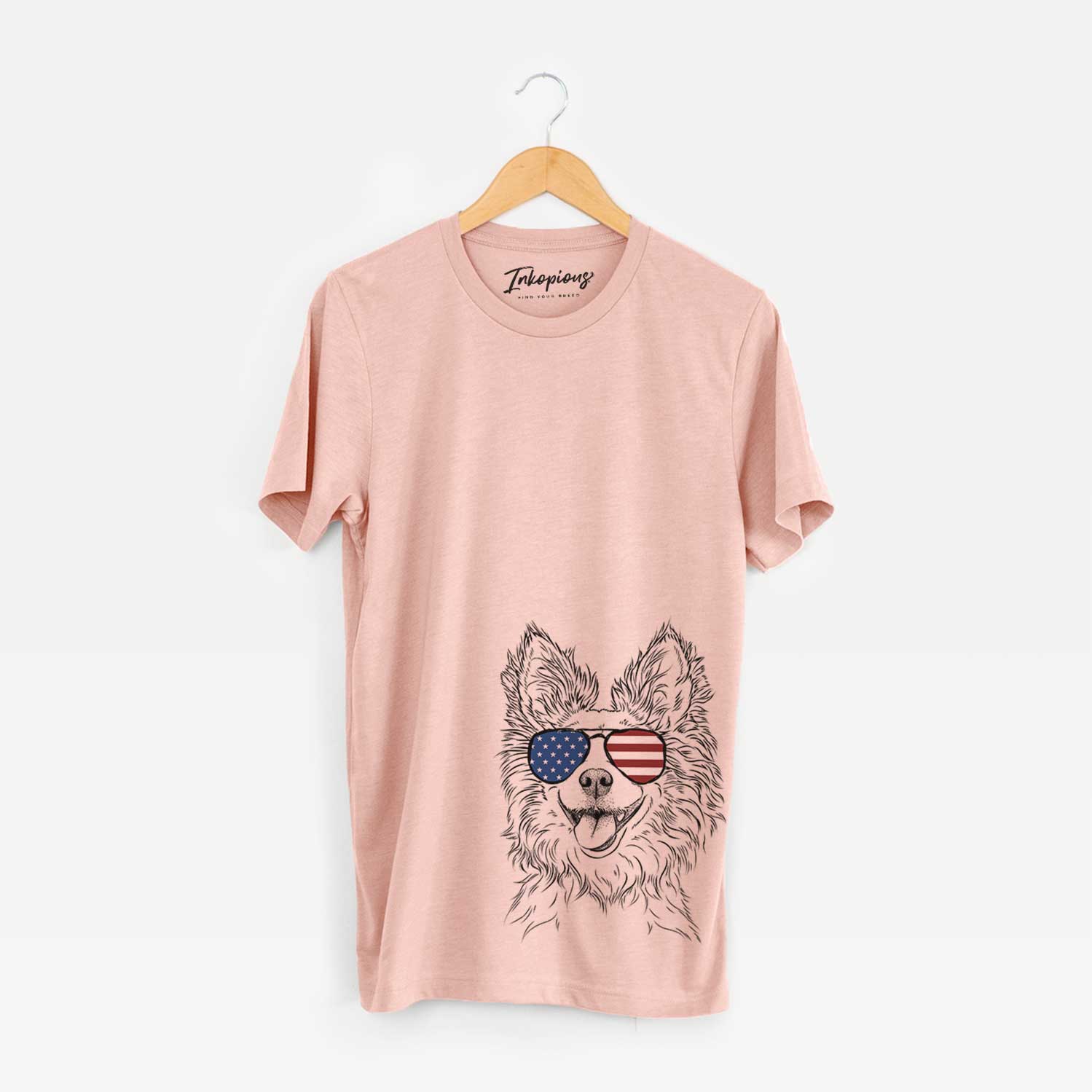 Hand-drawn sketch of Jasper the Pomchi wearing American flag sunglasses on a Peach Unisex crewneck