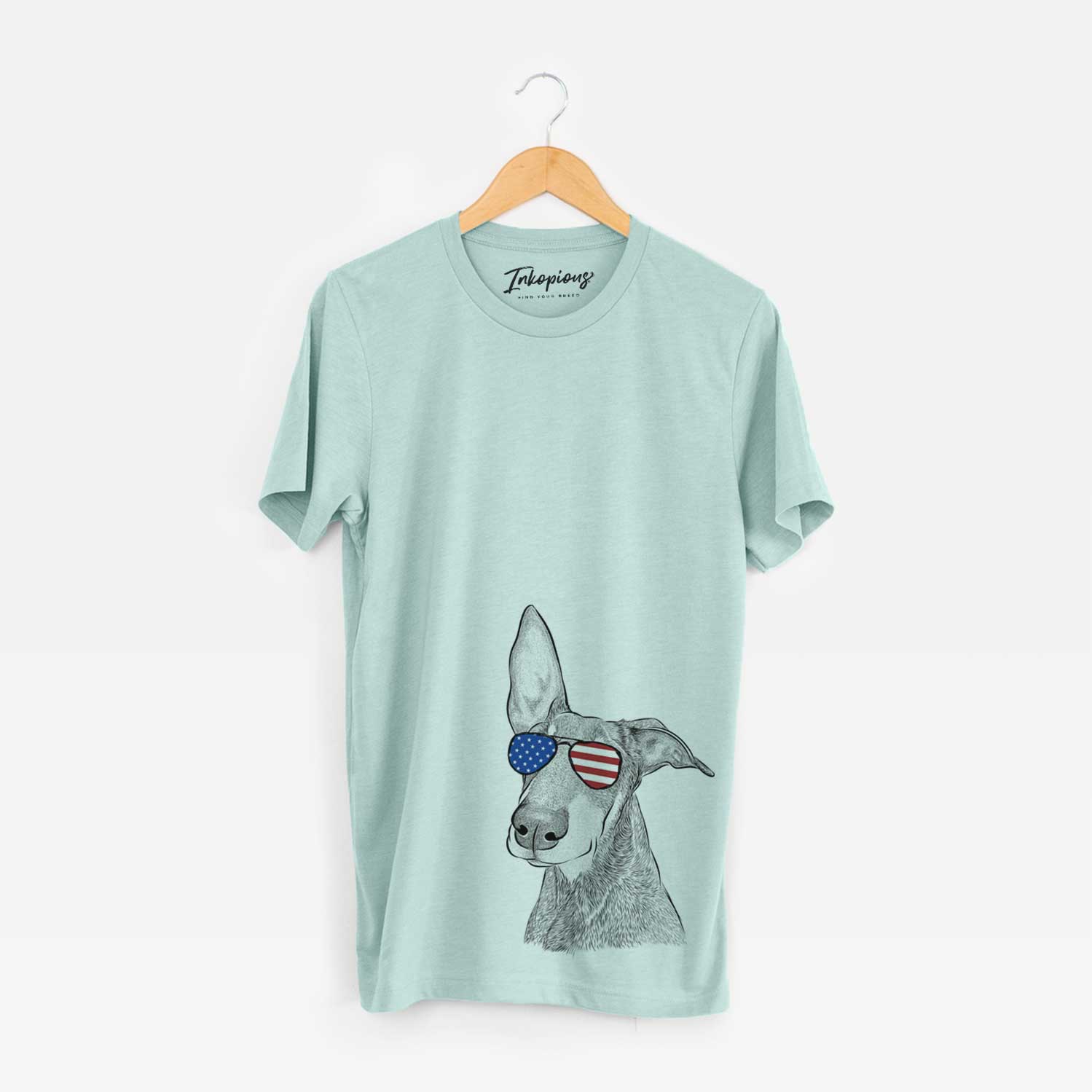 Hand-drawn sketch of Kain the Doberman Pinscher wearing American flag sunglasses on a Heather Sage Unisex crewneck