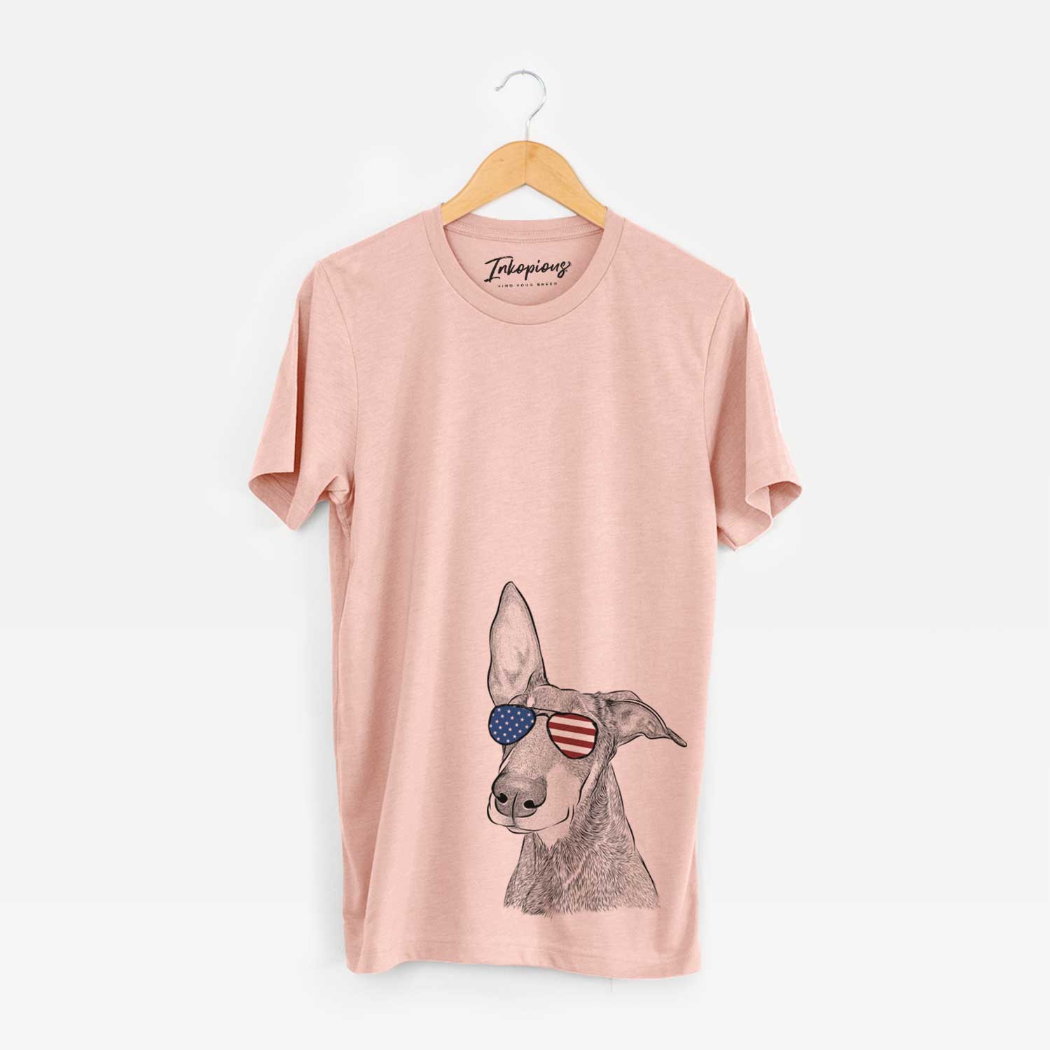 Hand-drawn sketch of Kain the Doberman Pinscher wearing American flag sunglasses on a Peach Unisex crewneck