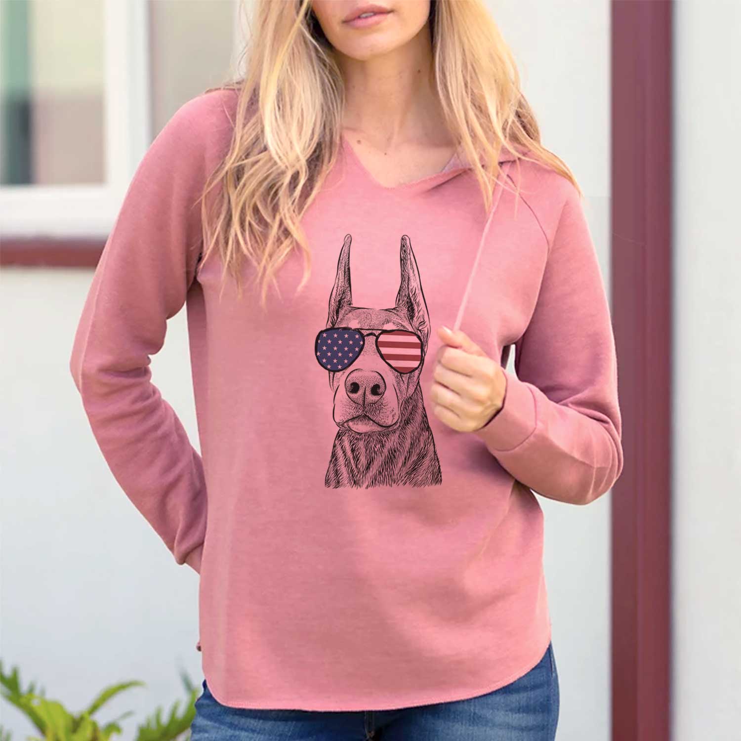 Hand-drawn sketch of Luna the Doberman Pinscher wearing American flag sunglasses on a Dusty Rose Cali Wave Hooded Sweatshirt, lifestyle photo