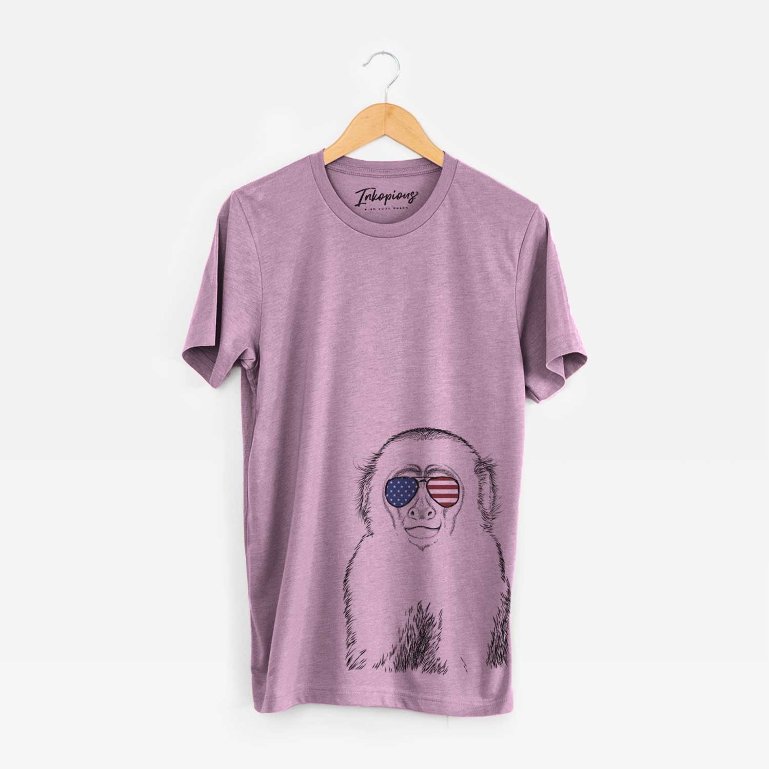 Hand-drawn sketch of Marcel the Capuchin Monkey wearing American flag sunglasses on an Orchid Unisex crewneck