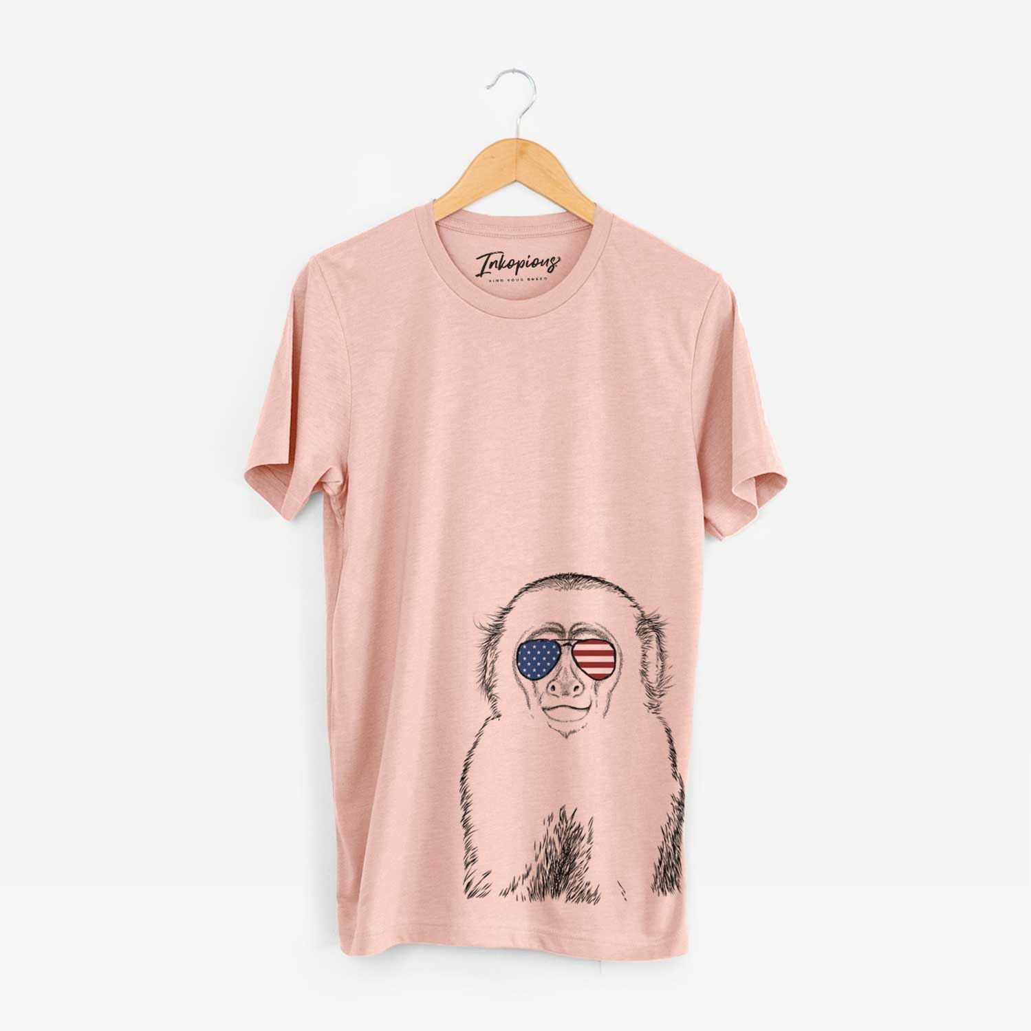 Hand-drawn sketch of Marcel the Capuchin Monkey wearing American flag sunglasses on a Peach Unisex crewneck