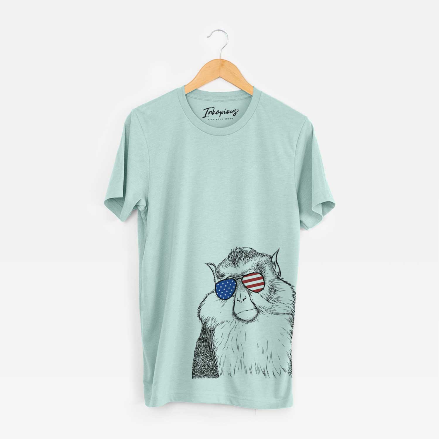 Hand-drawn sketch of Matata the Mona Monkey wearing American flag sunglasses on a Heather Sage Unisex crewneck