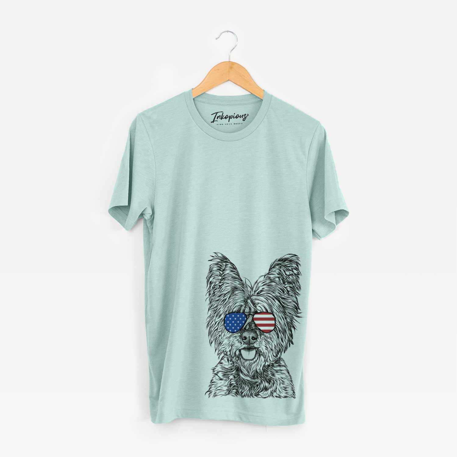 Hand-drawn sketch of McDuff the Cairn Terrier wearing American flag sunglasses on a Heather Sage Unisex crewneck