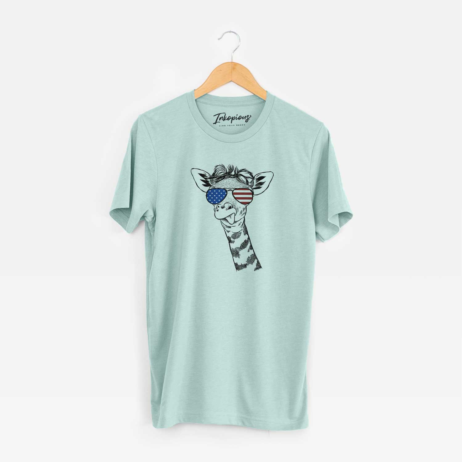 Hand-drawn sketch of Mel the Baby Giraffe wearing American flag sunglasses on a Heather Sage Unisex crewneck