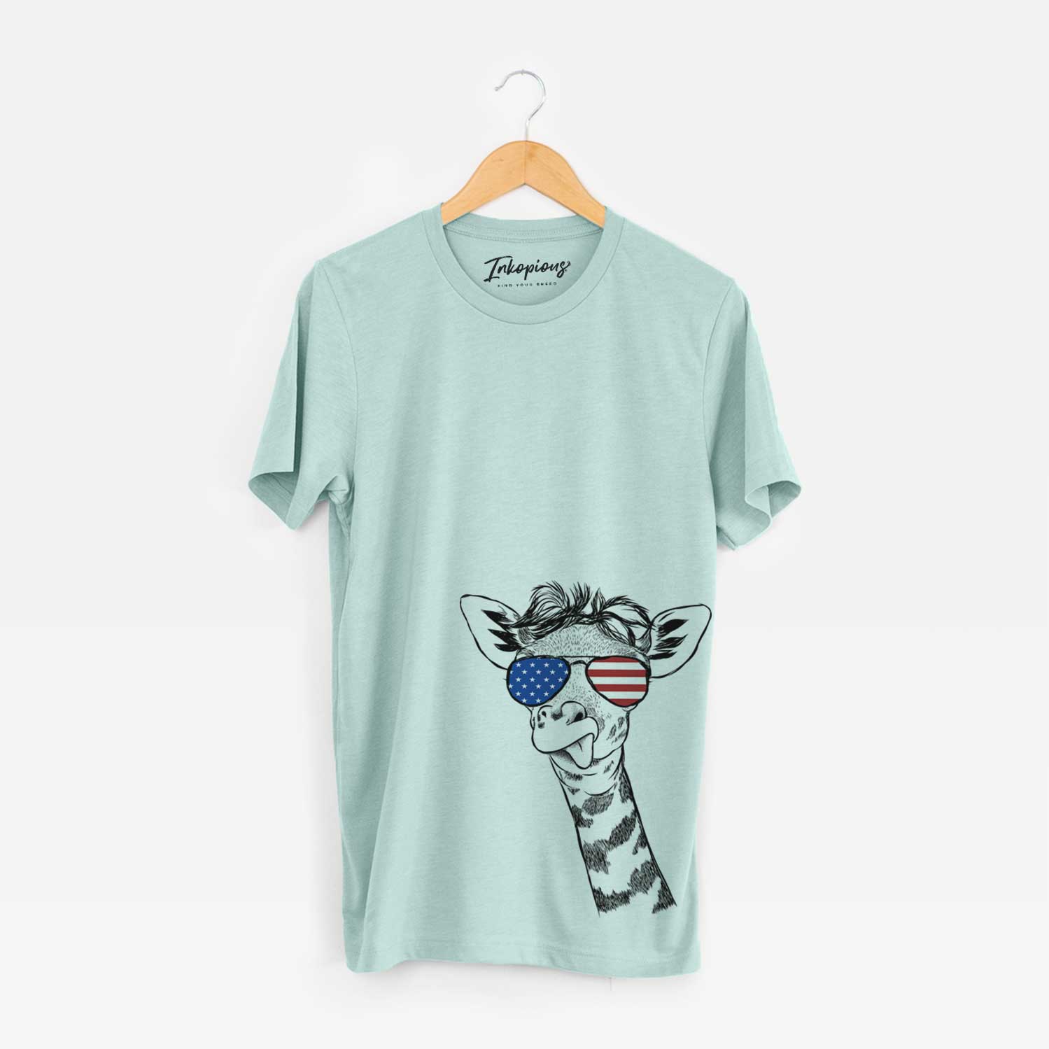 Hand-drawn sketch of Mel the Baby Giraffe wearing American flag sunglasses on a Heather Sage Unisex crewneck