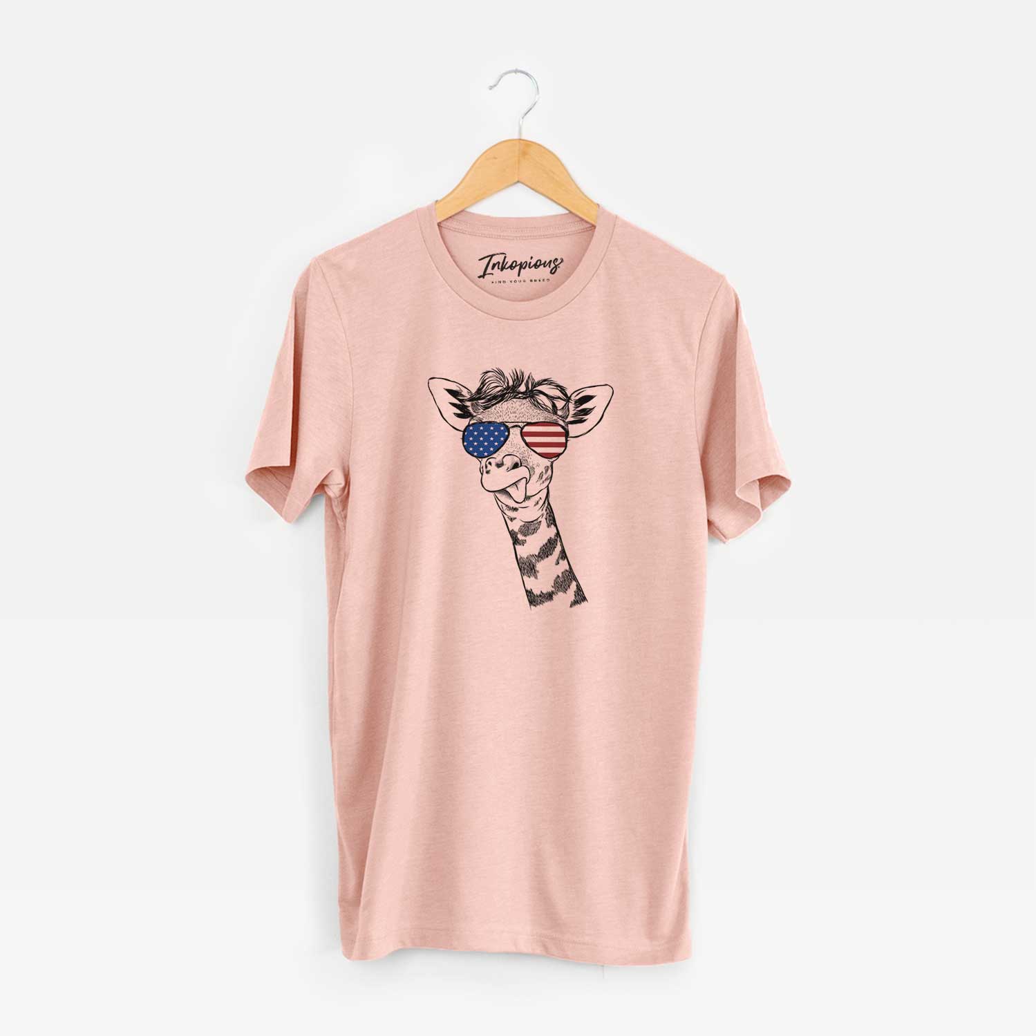 Hand-drawn sketch of Mel the Baby Giraffe wearing American flag sunglasses on a Peach Unisex crewneck