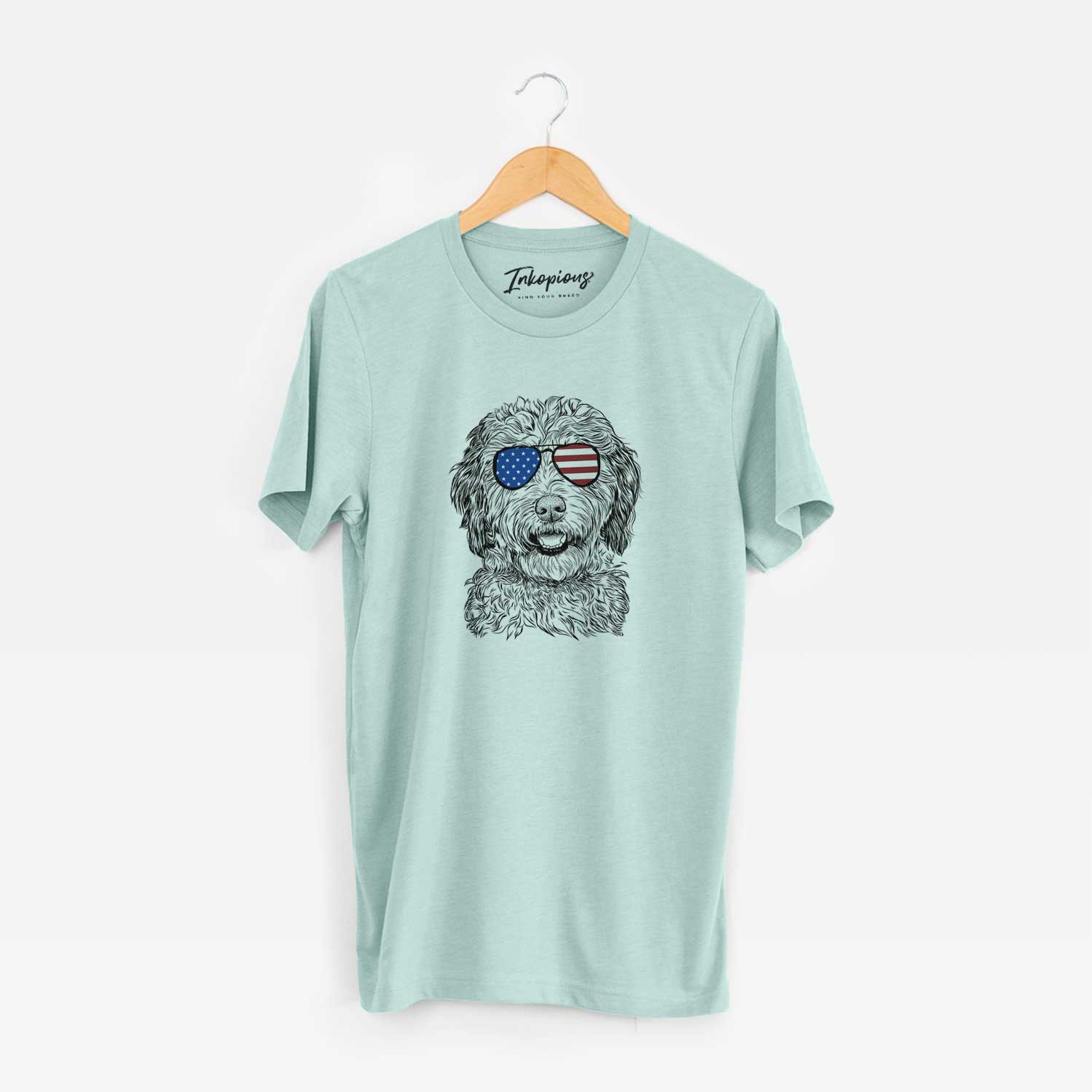 Hand-drawn sketch of Palmer the Aussiedoodle wearing American flag sunglasses on a Heather Sage Unisex crewneck