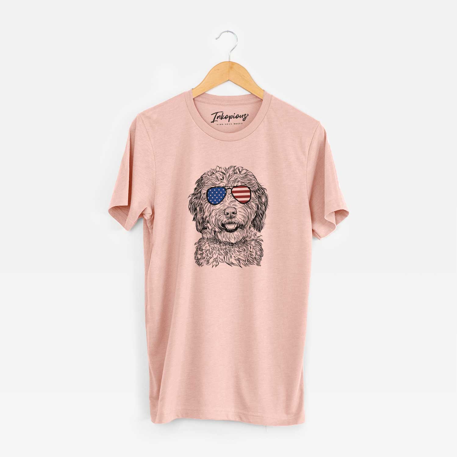 Hand-drawn sketch of Palmer the Aussiedoodle wearing American flag sunglasses on a Peach Unisex crewneck