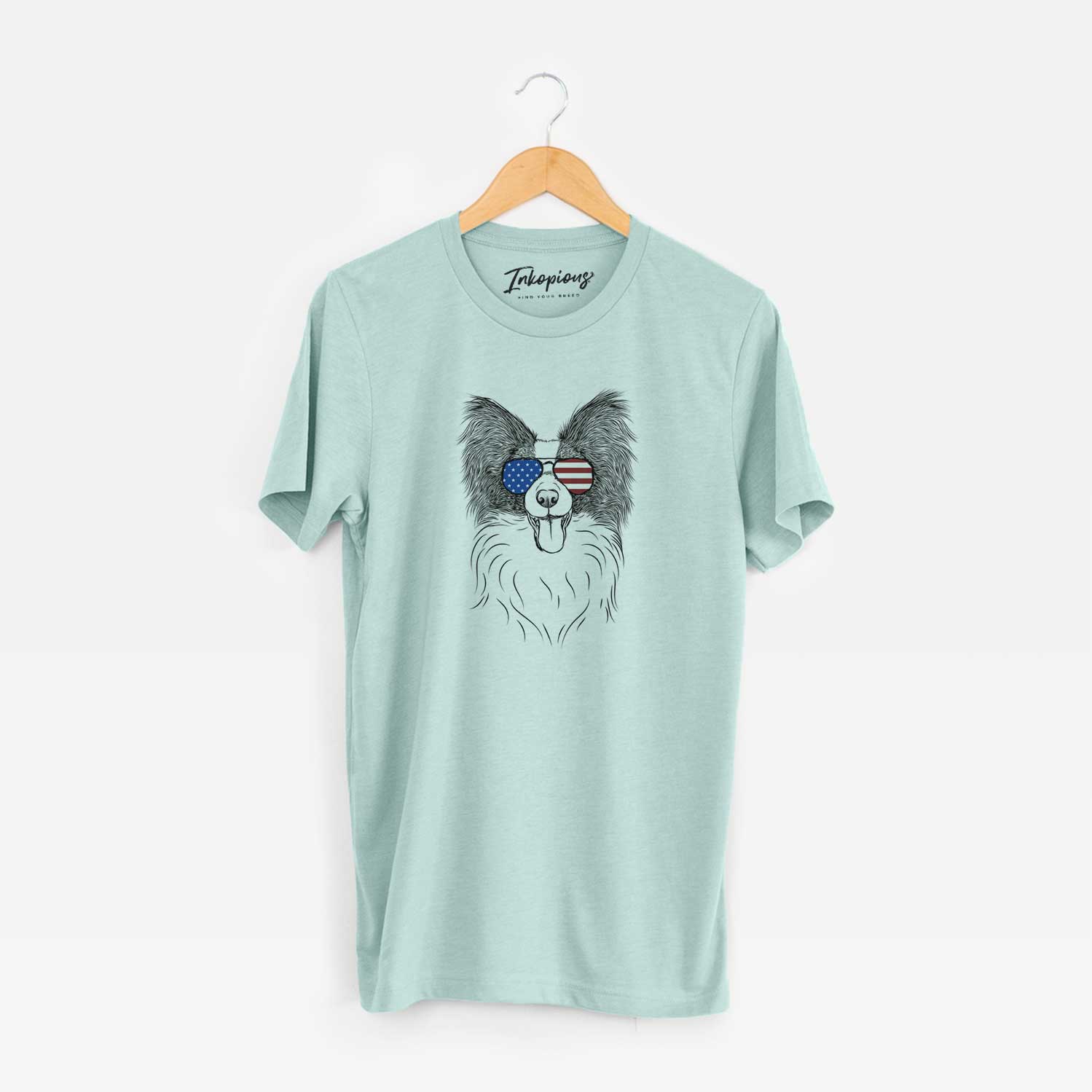 Hand-drawn sketch of Patrick the Papillon wearing American flag sunglasses on a Heather Sage Unisex crewneck